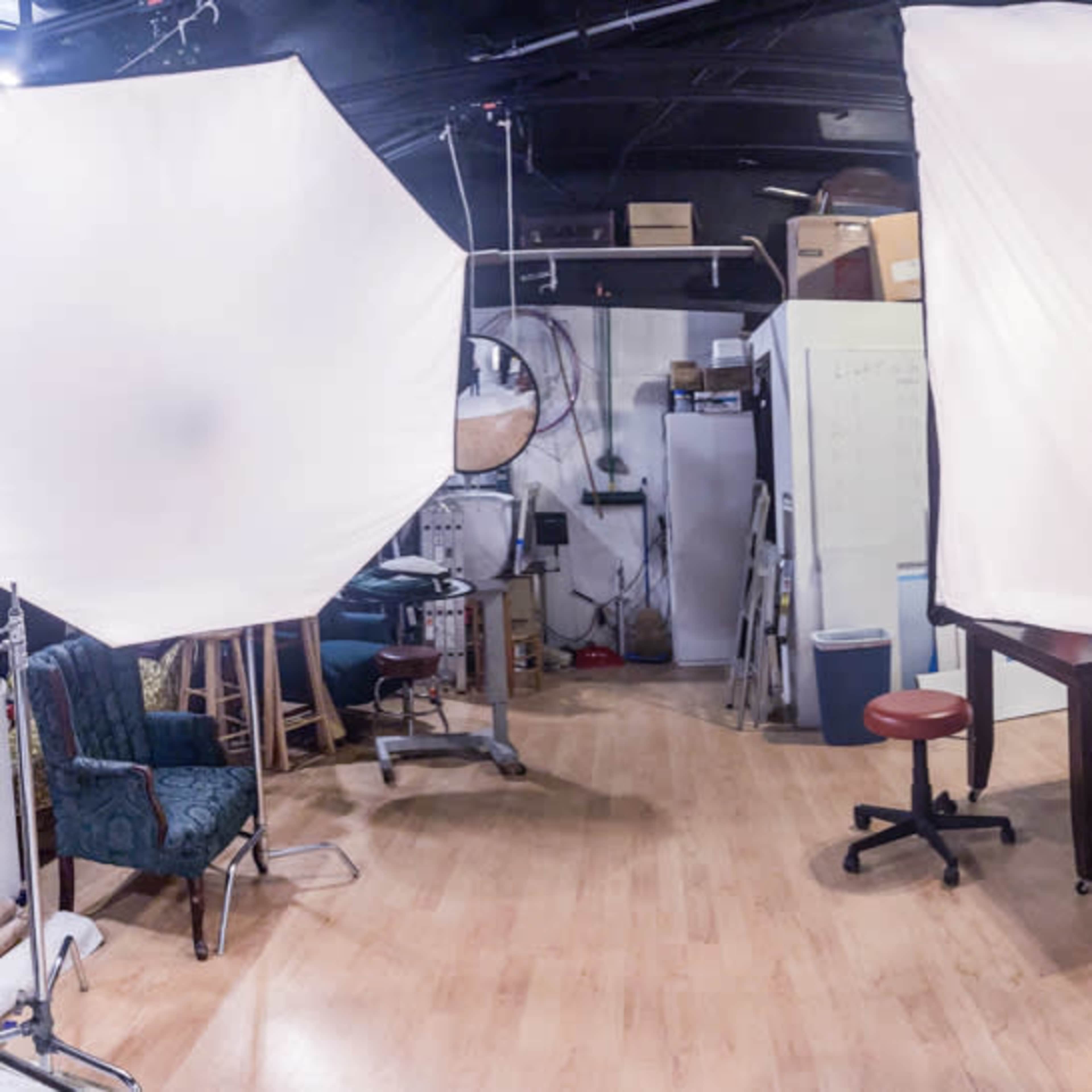 A studio space with two large softbox lights, a table, and various equipment, including a chair and a blue cabinet.