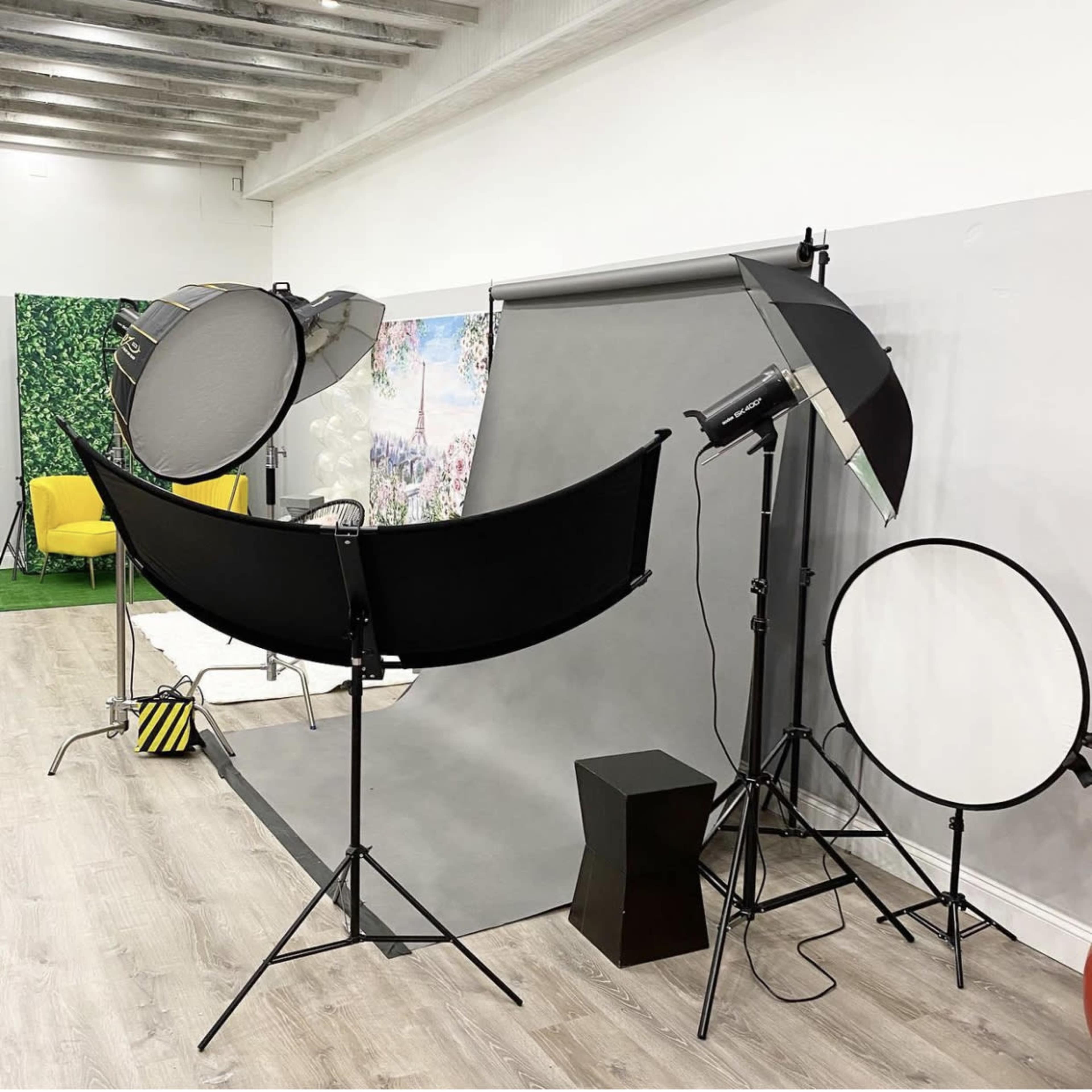 A photography setup featuring backdrop stands, lighting equipment, and a variety of light modifiers in a studio environment.