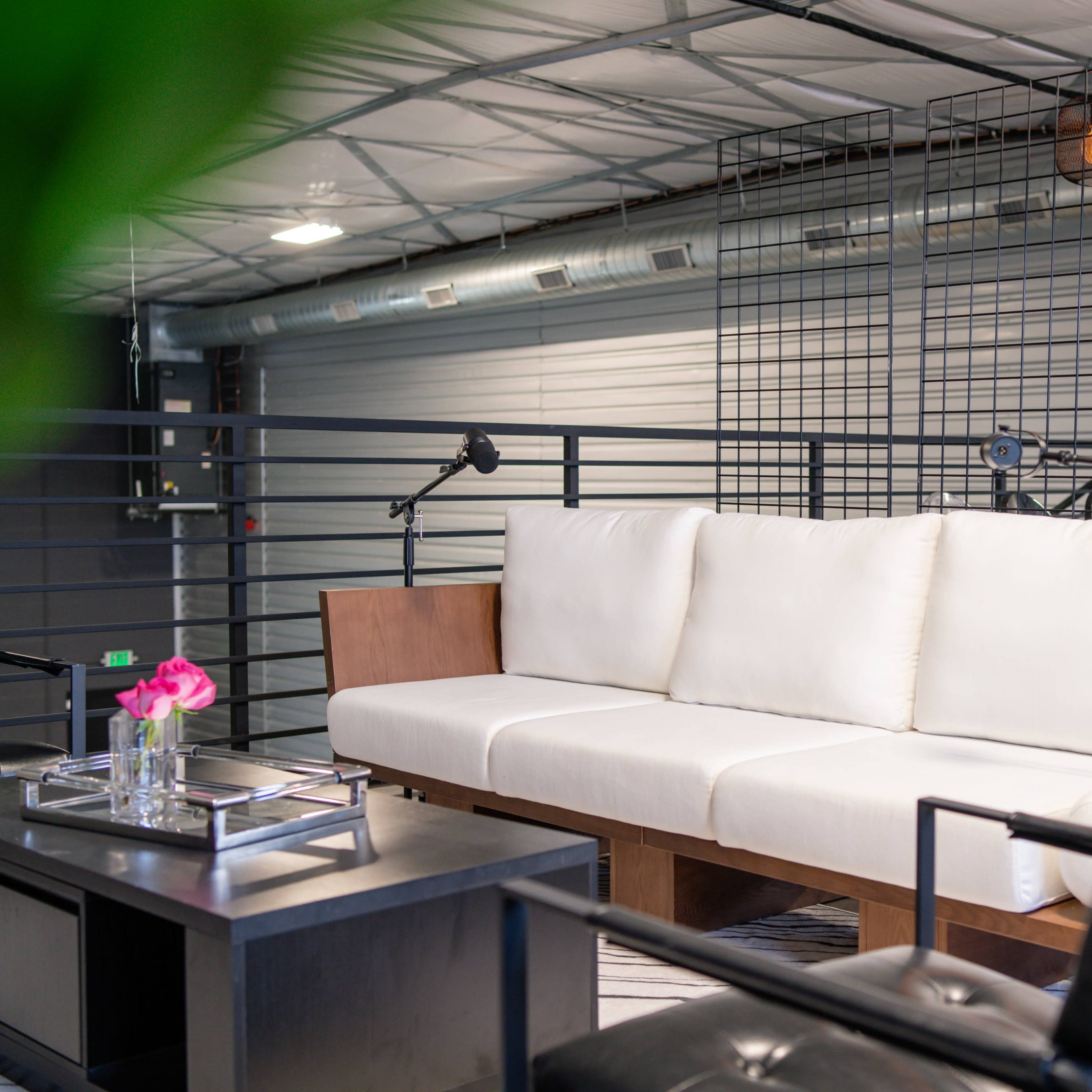 A modern seating area with a white sofa, a black coffee table, and pendant lights in an industrial-style space.