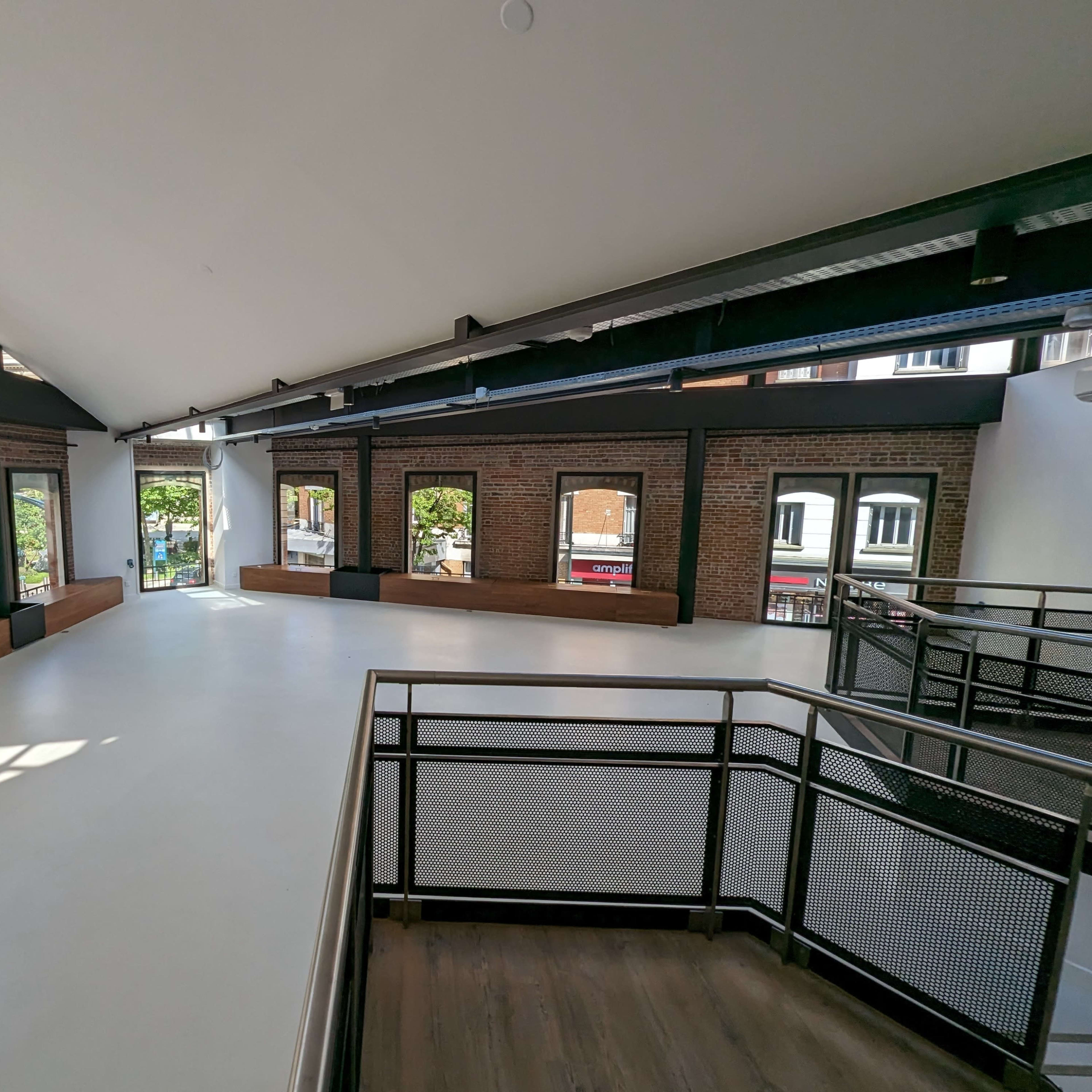 An open, spacious interior with high ceilings, large windows, and a blend of brick and modern architectural elements.