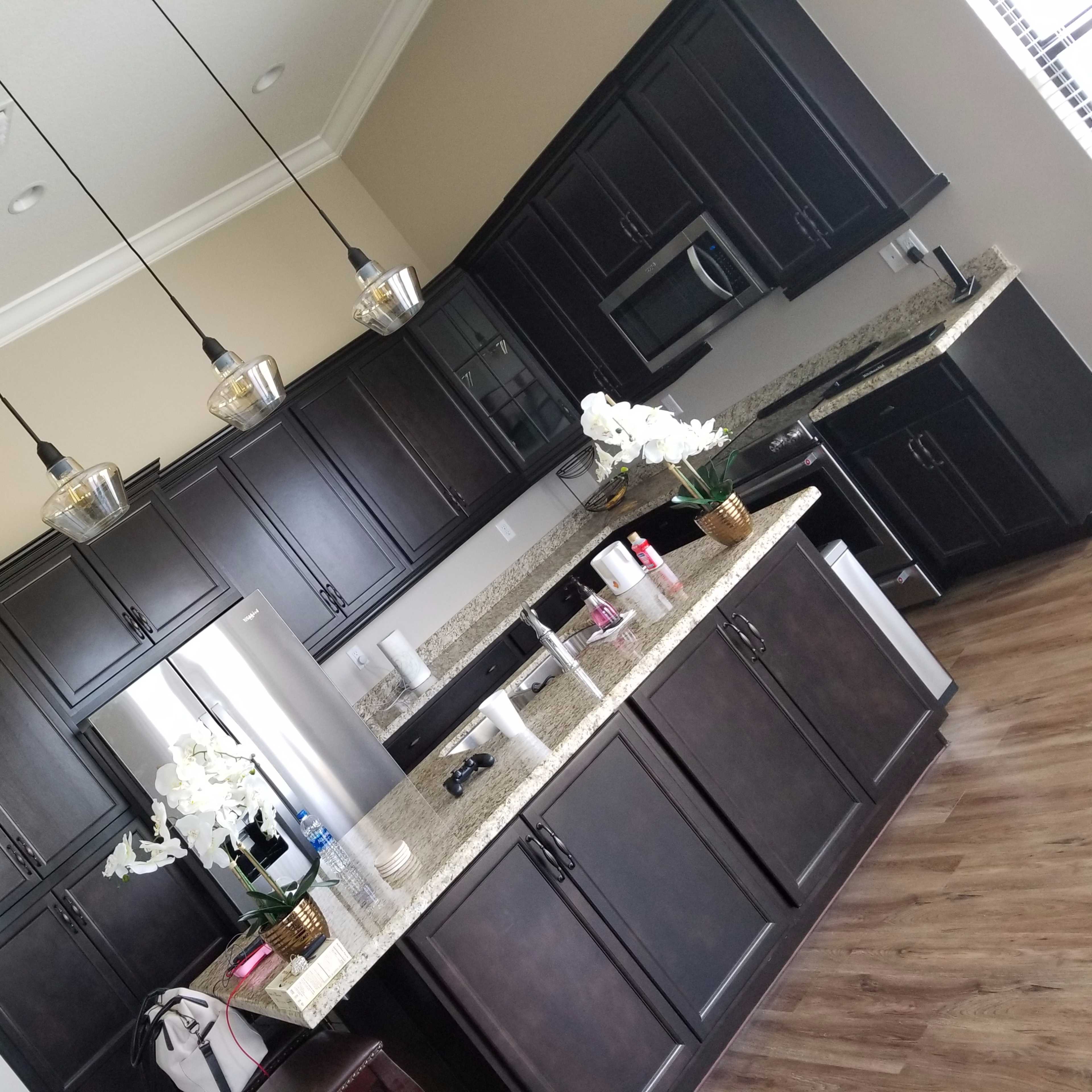 A modern kitchen with dark wooden cabinets, a granite countertop, and pendant lights hanging above the island.