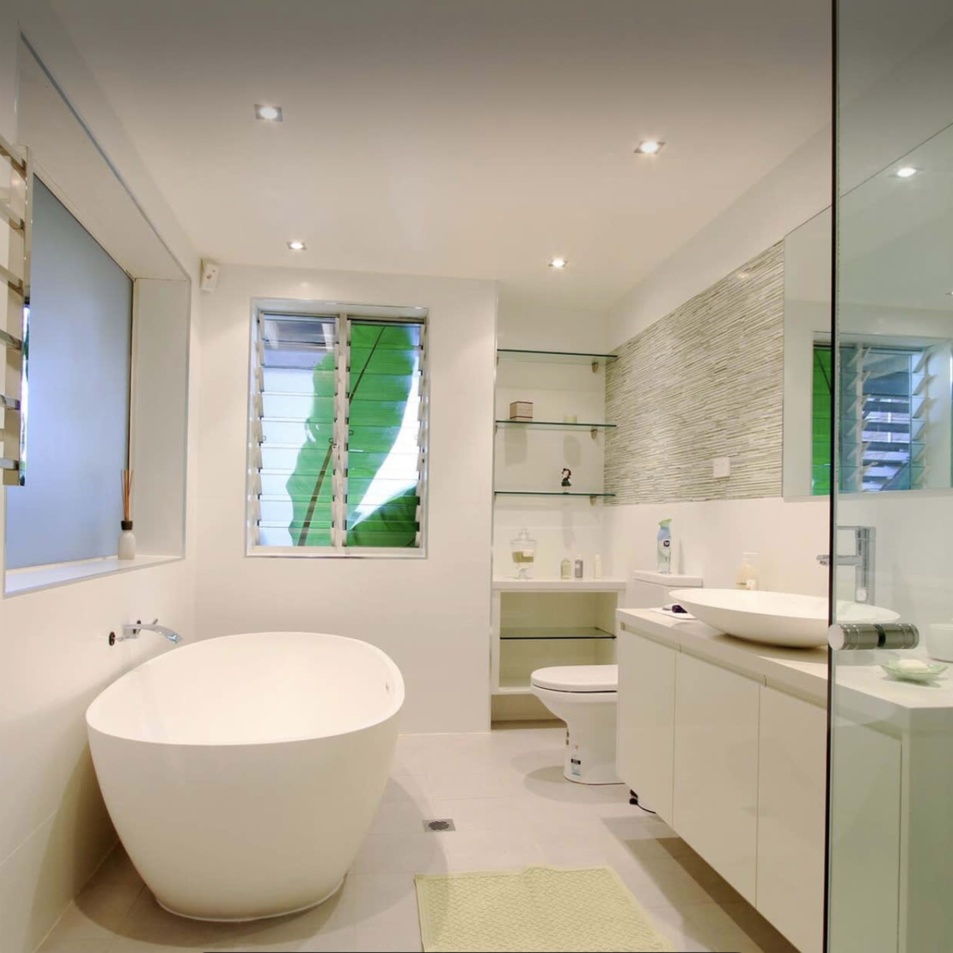 A modern bathroom featuring a freestanding bathtub, a glass-enclosed shower, a wall-mounted sink, and a toilet, all complemented by contemporary design elements.