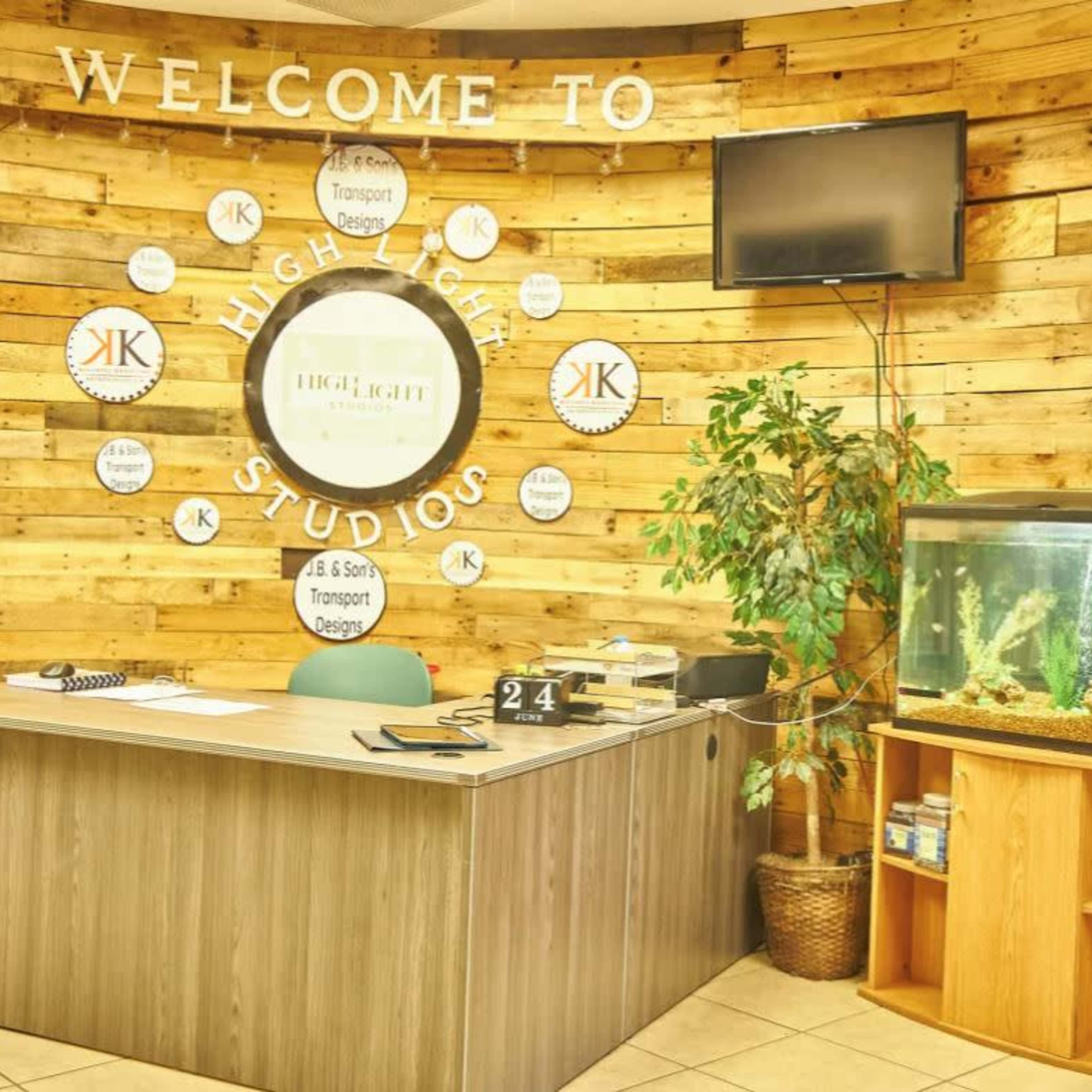 A reception area with a wooden wall, a desk with a notepad, number sign, and a fish tank nearby.