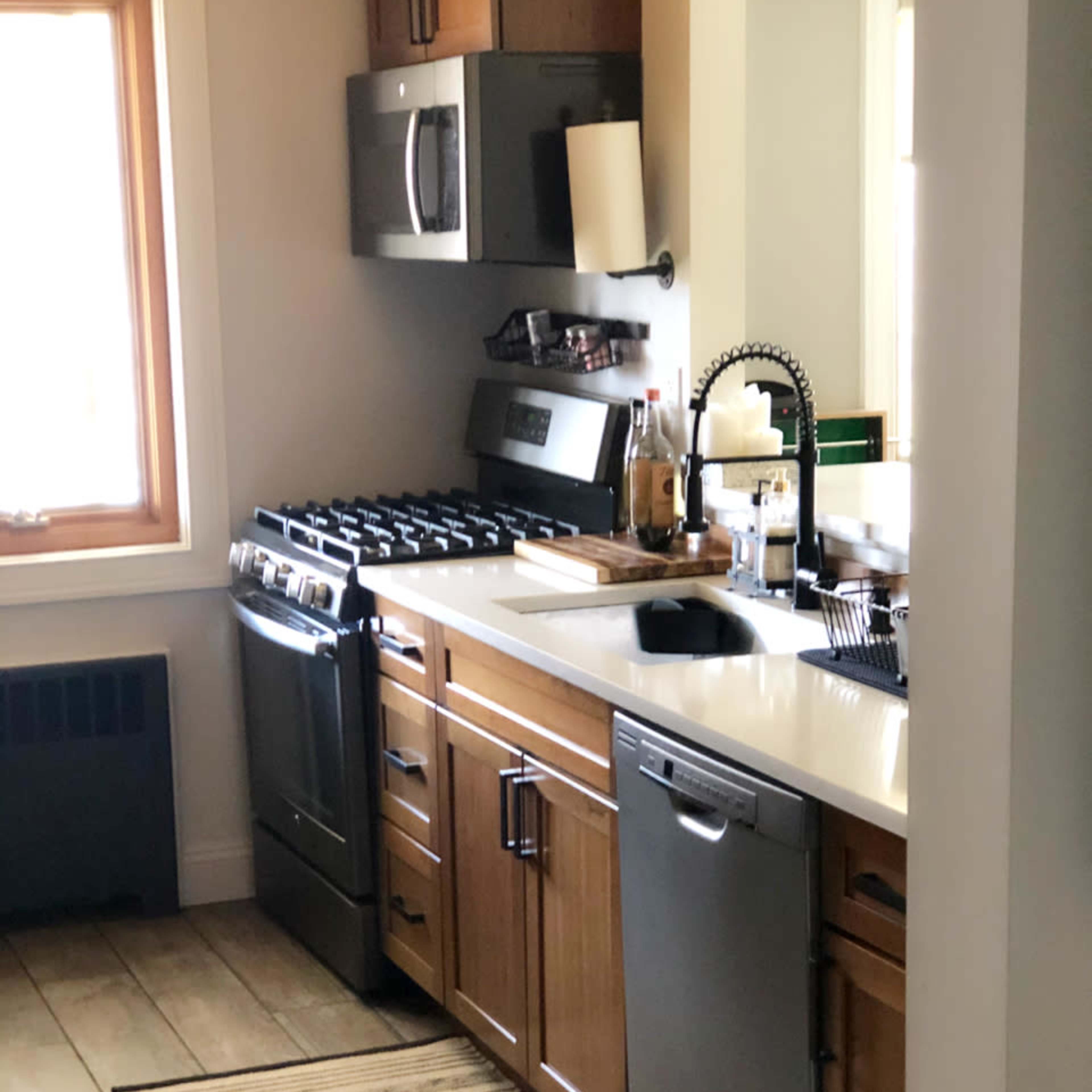 The kitchen features wooden cabinets, stainless steel appliances, and a double sink with a nearby window.