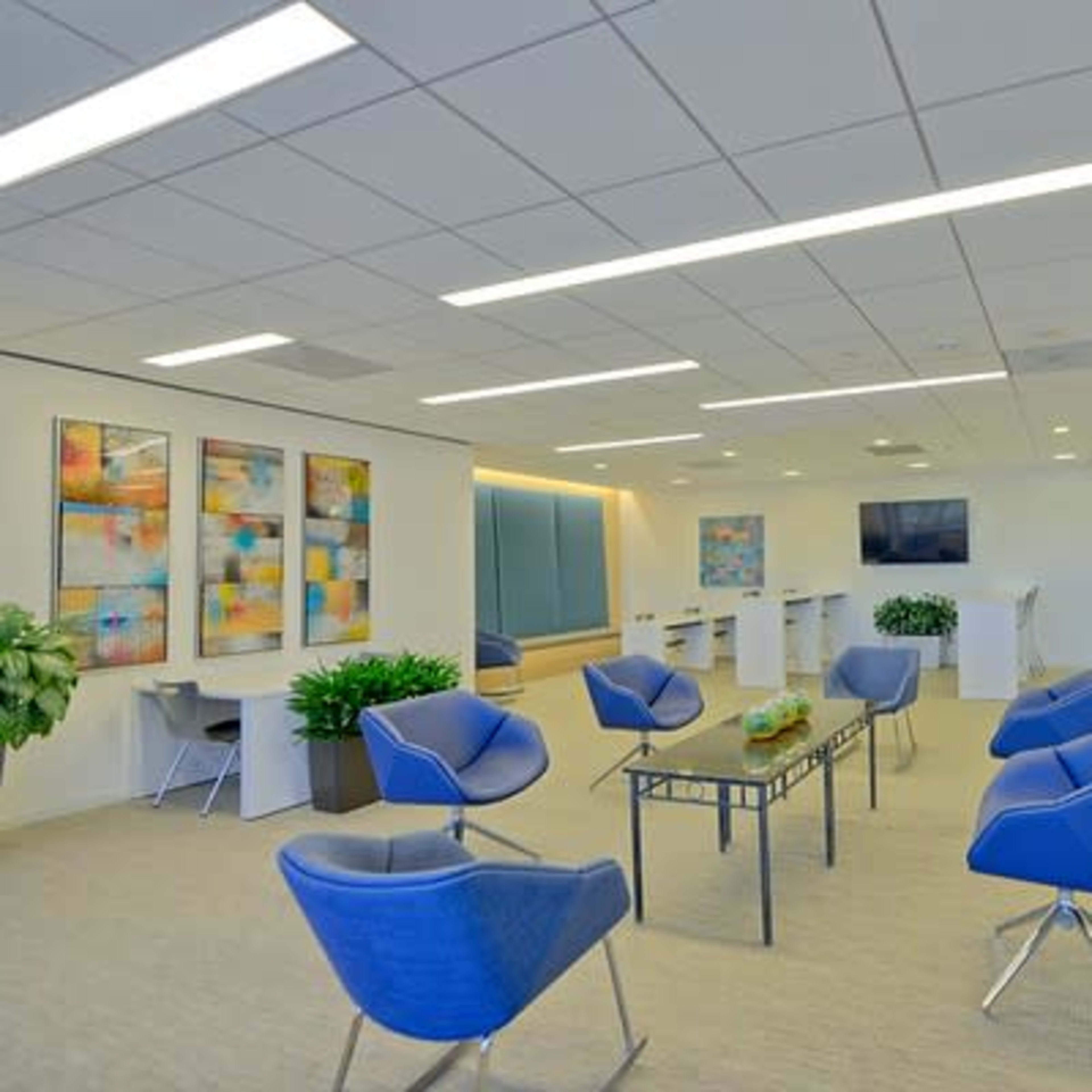 A modern office space featuring several blue chairs, a table in the center, and colorful artwork on the walls.