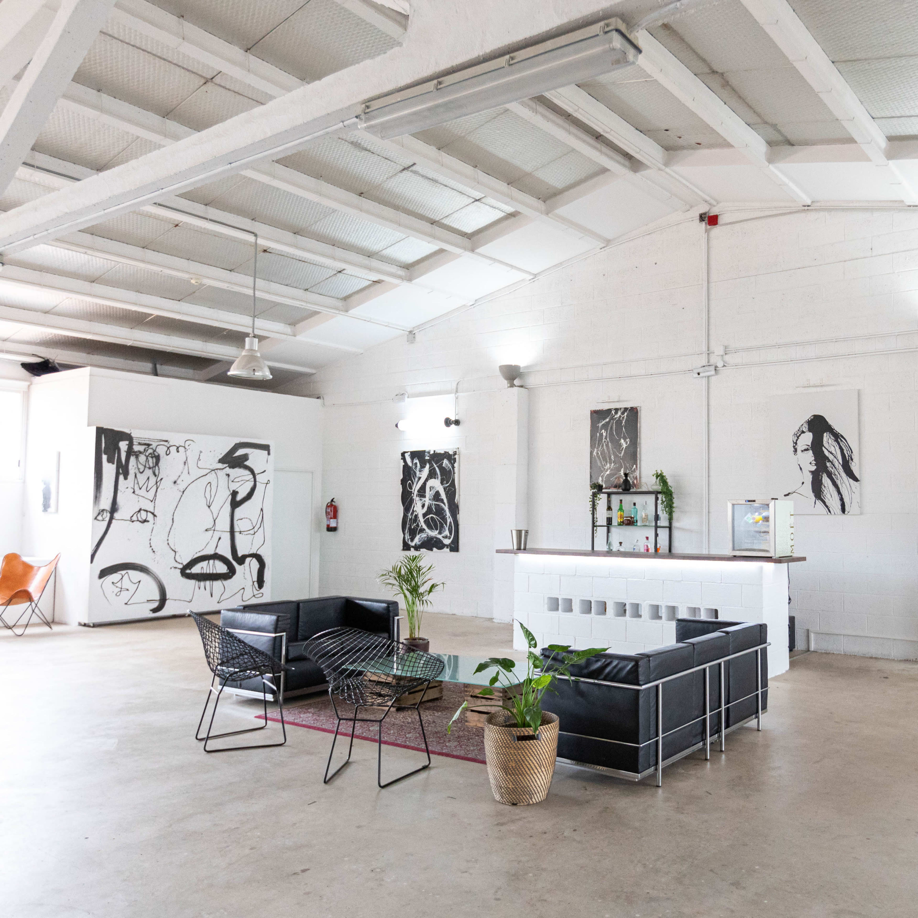 A spacious, minimalist interior with modern furniture, large artwork on the walls, and ample natural light.