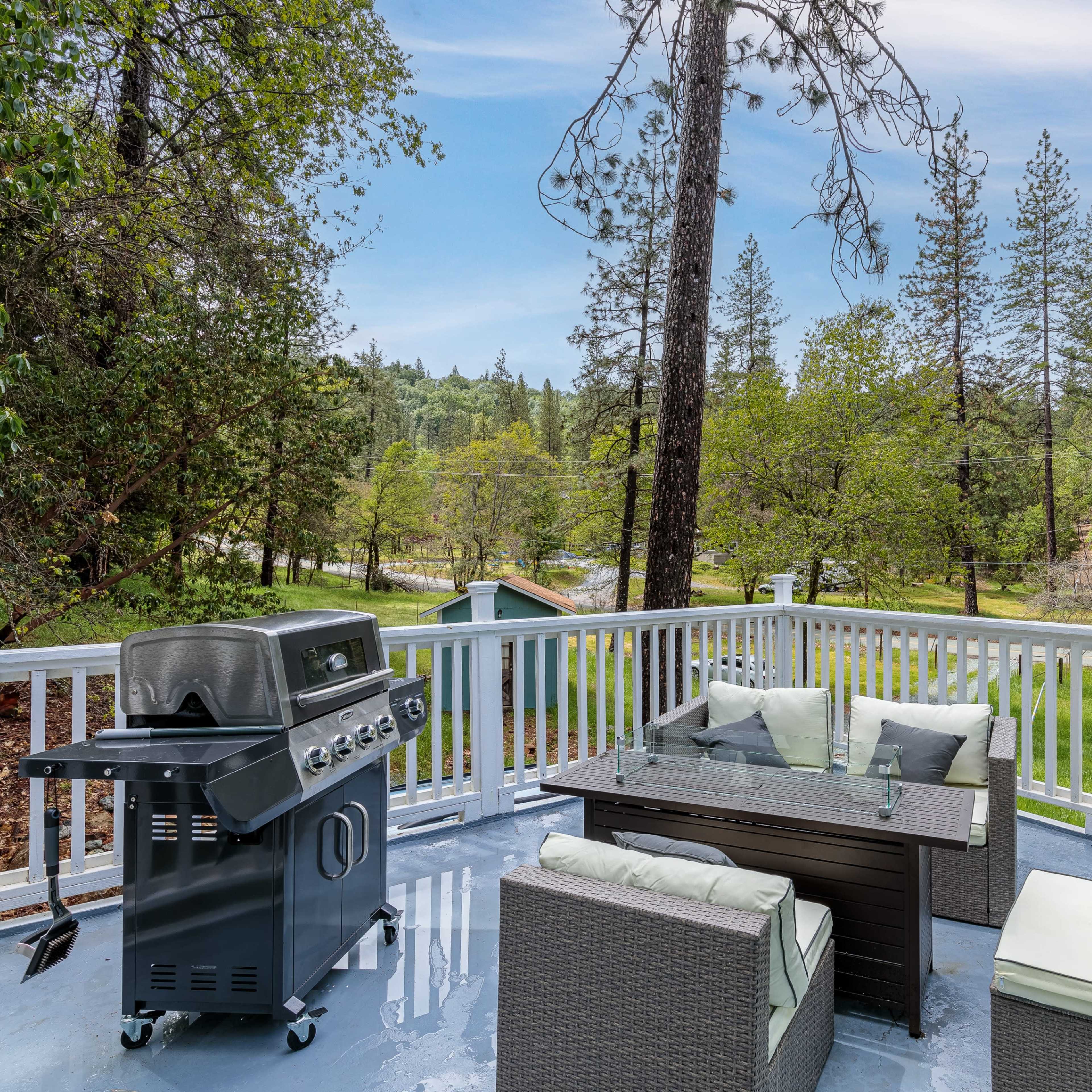 A deck features a barbecue grill and outdoor seating amidst a backdrop of trees and greenery.