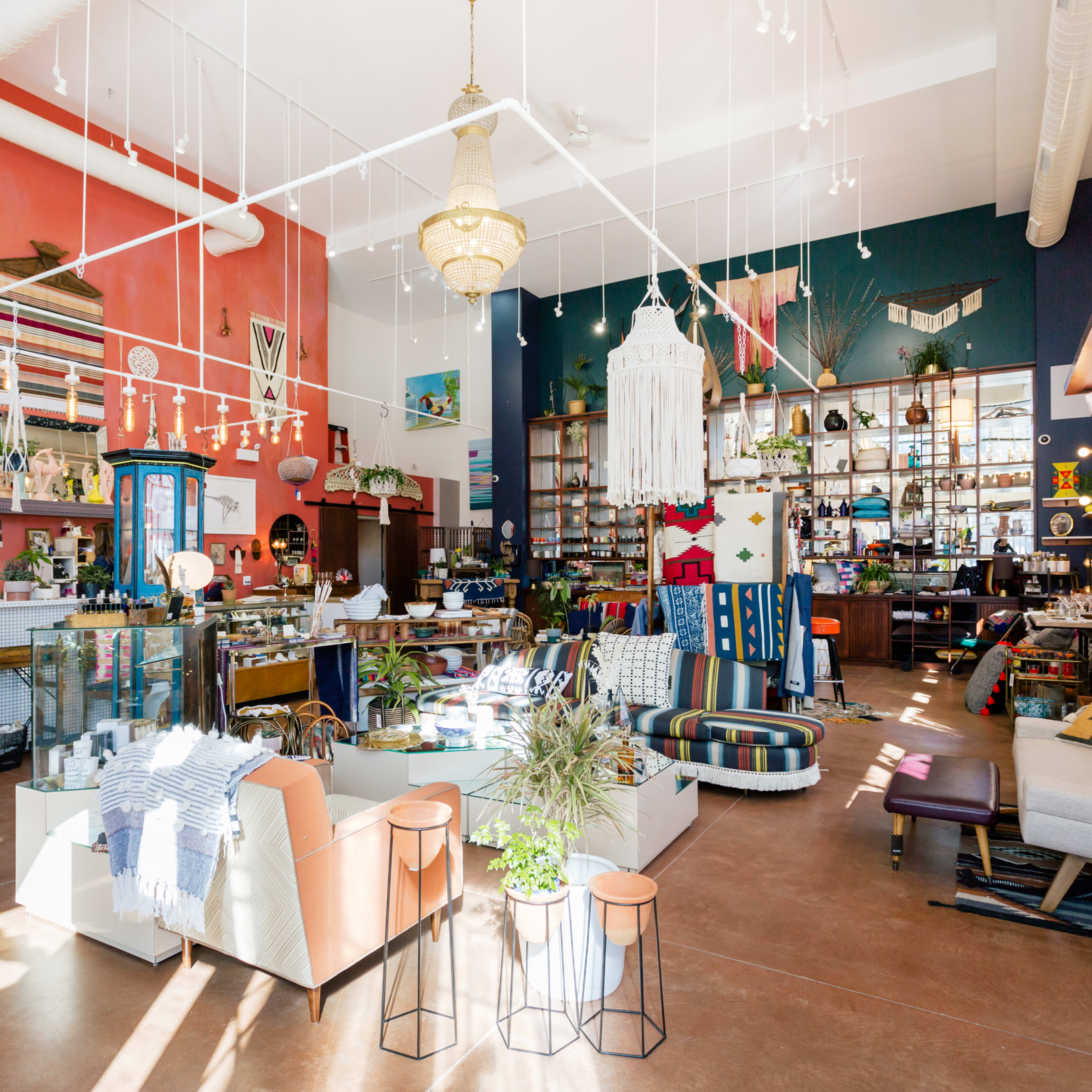 A brightly lit retail space filled with eclectic furniture, decorative items, and displays of various products.