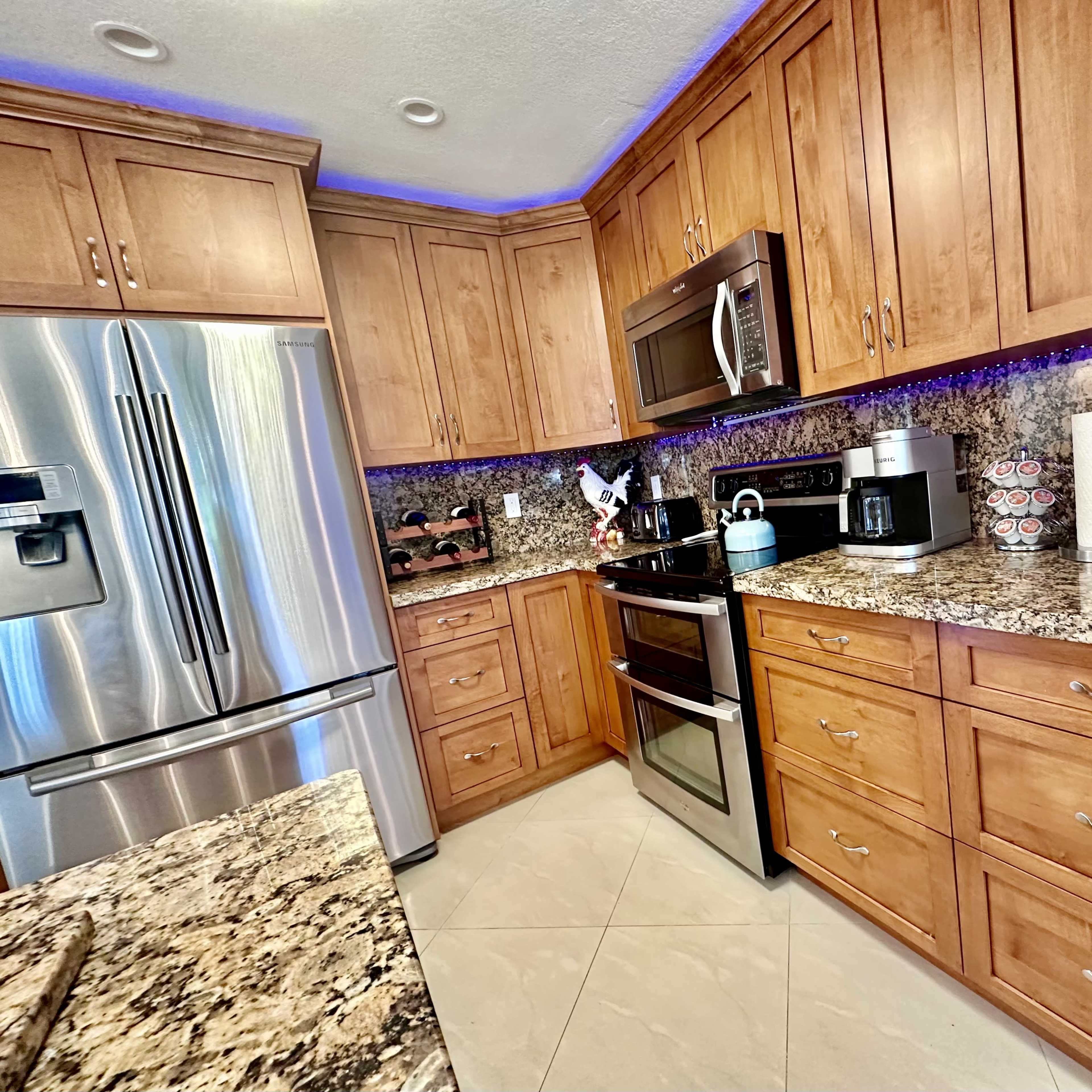 A modern kitchen with wooden cabinets, stainless steel appliances, and a granite countertop.