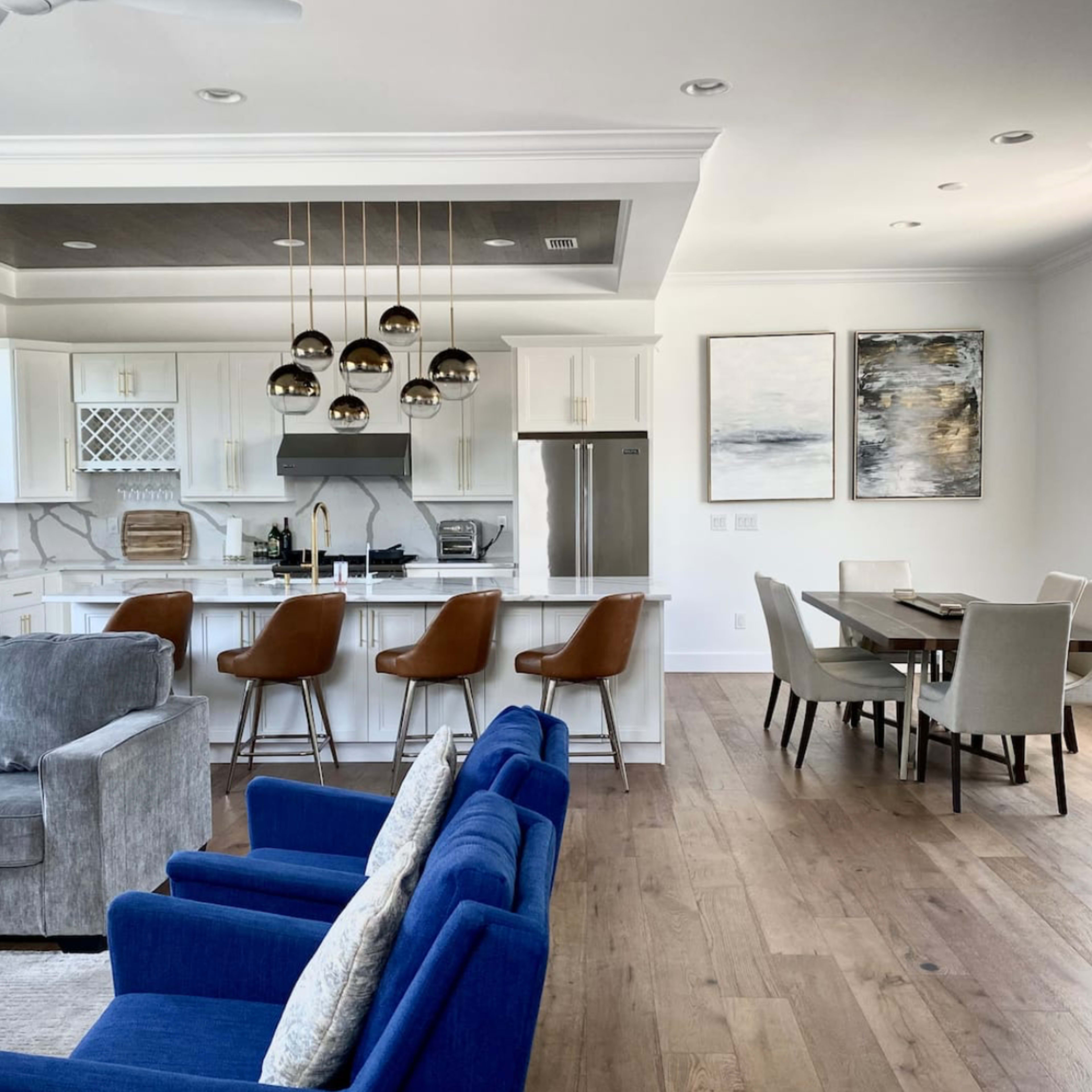 A modern kitchen and dining area with a seating arrangement, featuring a kitchen island with bar stools and a dining table nearby.