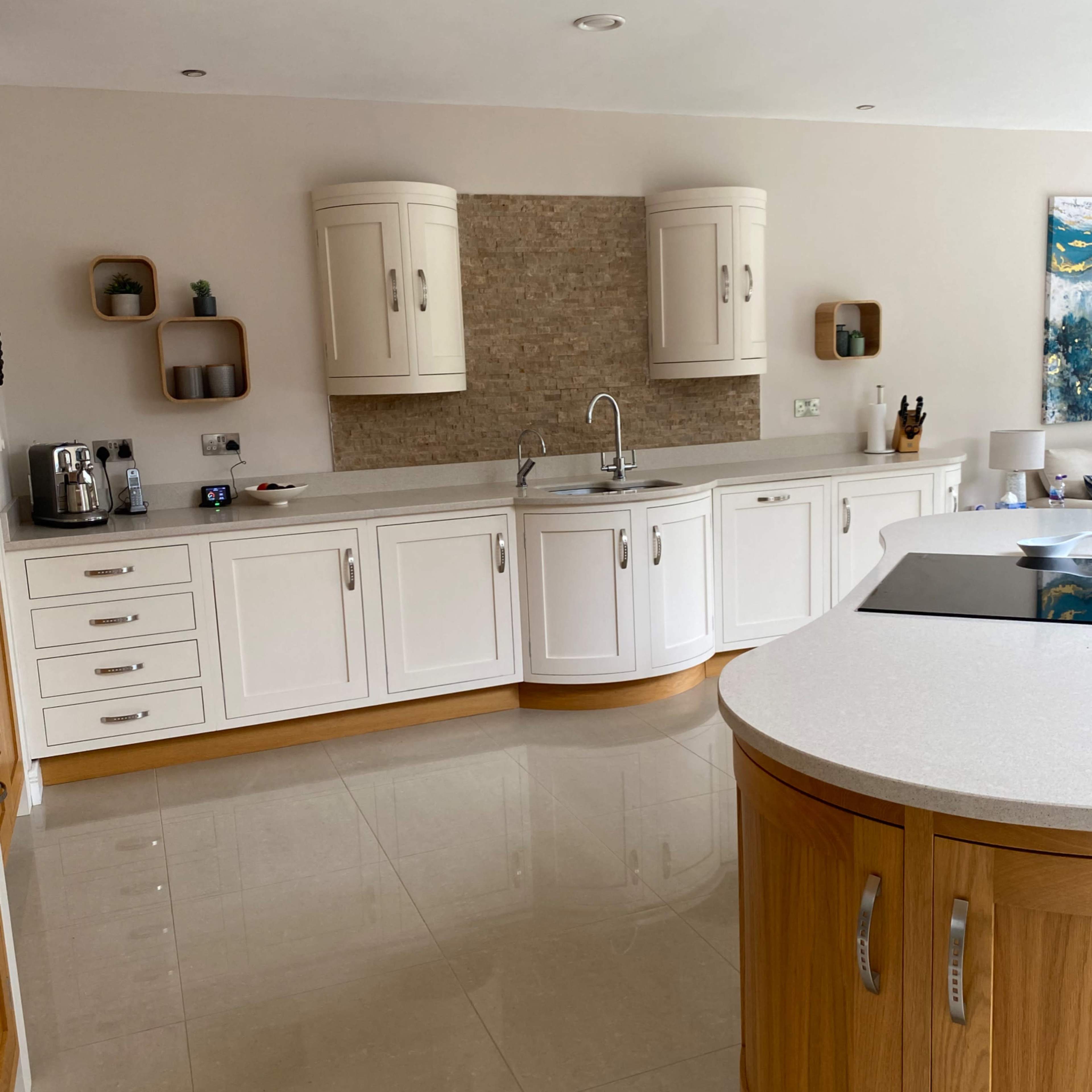A modern kitchen features white cabinetry, a stone backsplash, and a central island with a wooden finish.