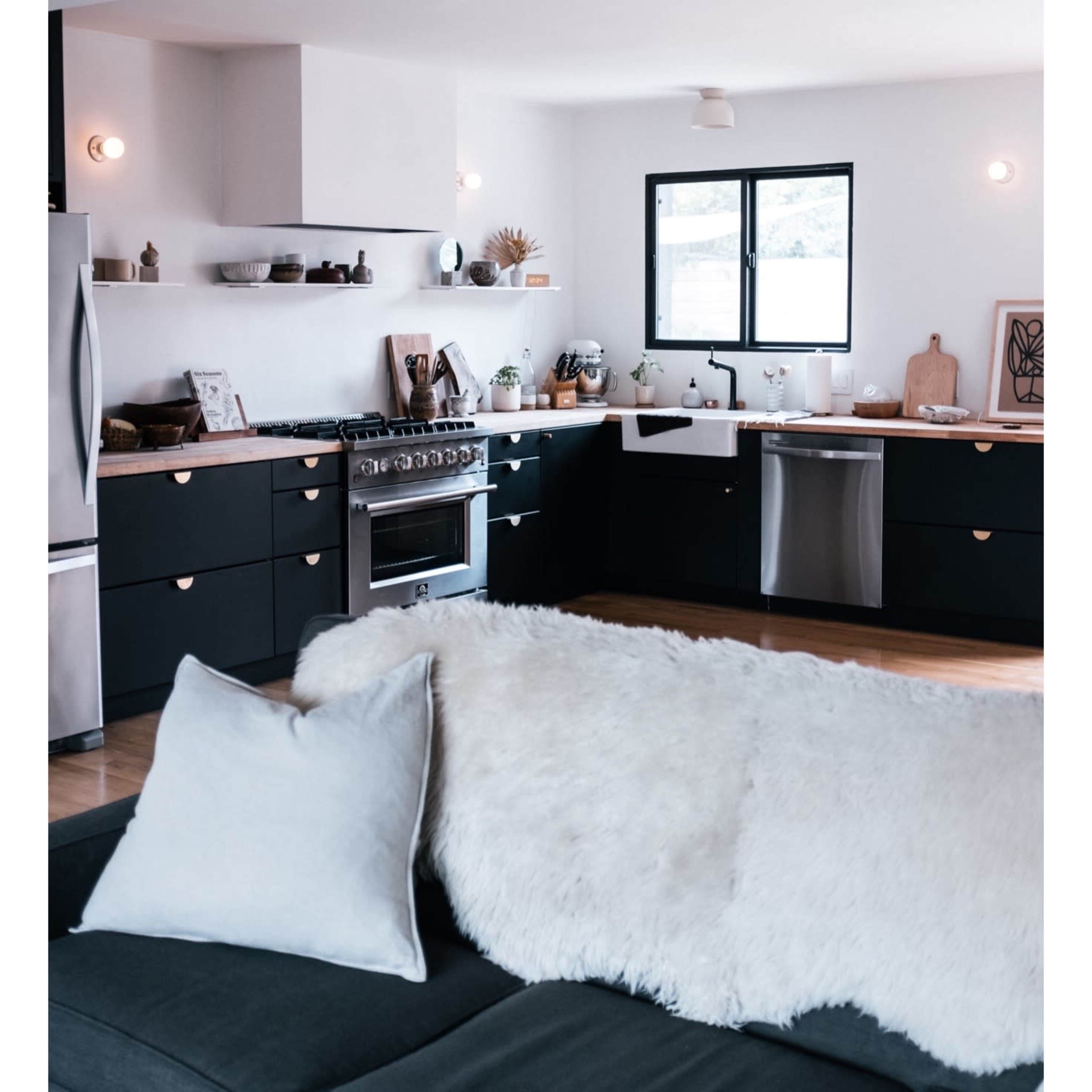 A modern kitchen featuring dark cabinets, stainless steel appliances, and a window with natural light illuminating the space.