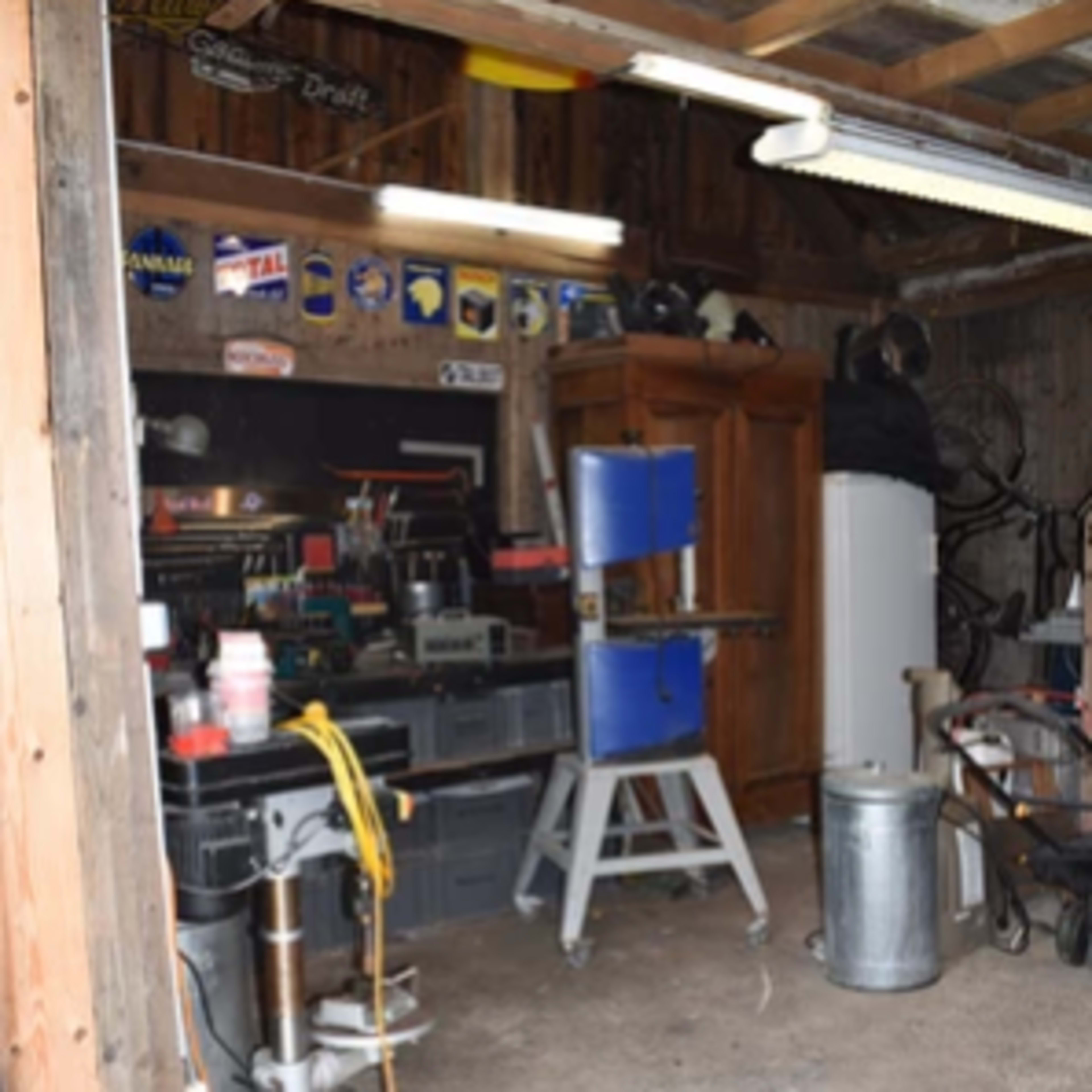 A garage workspace contains various tools, storage units, and equipment arranged along the walls and floor.