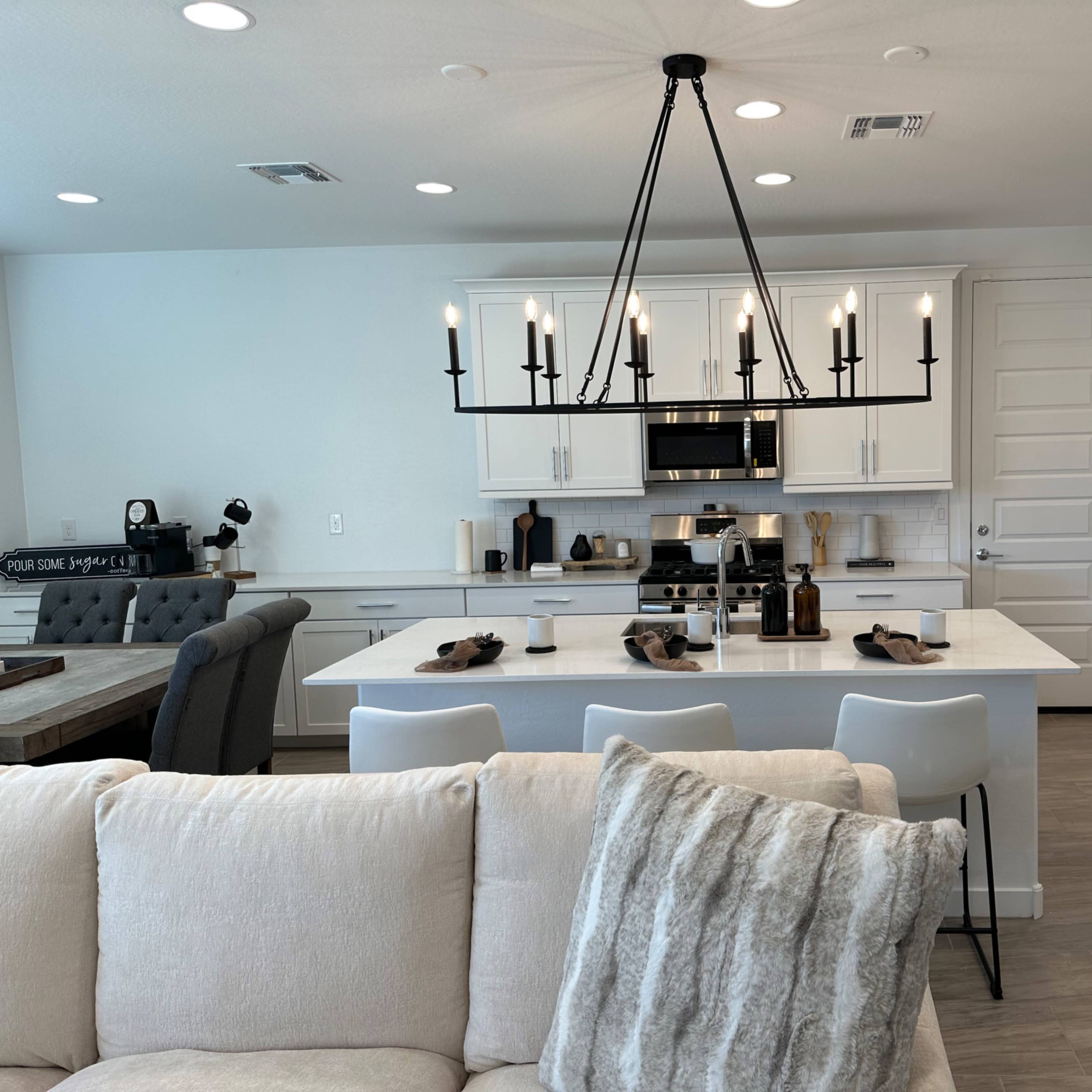 A modern kitchen features white cabinets, a large island with seating, and a pendant light hanging overhead.