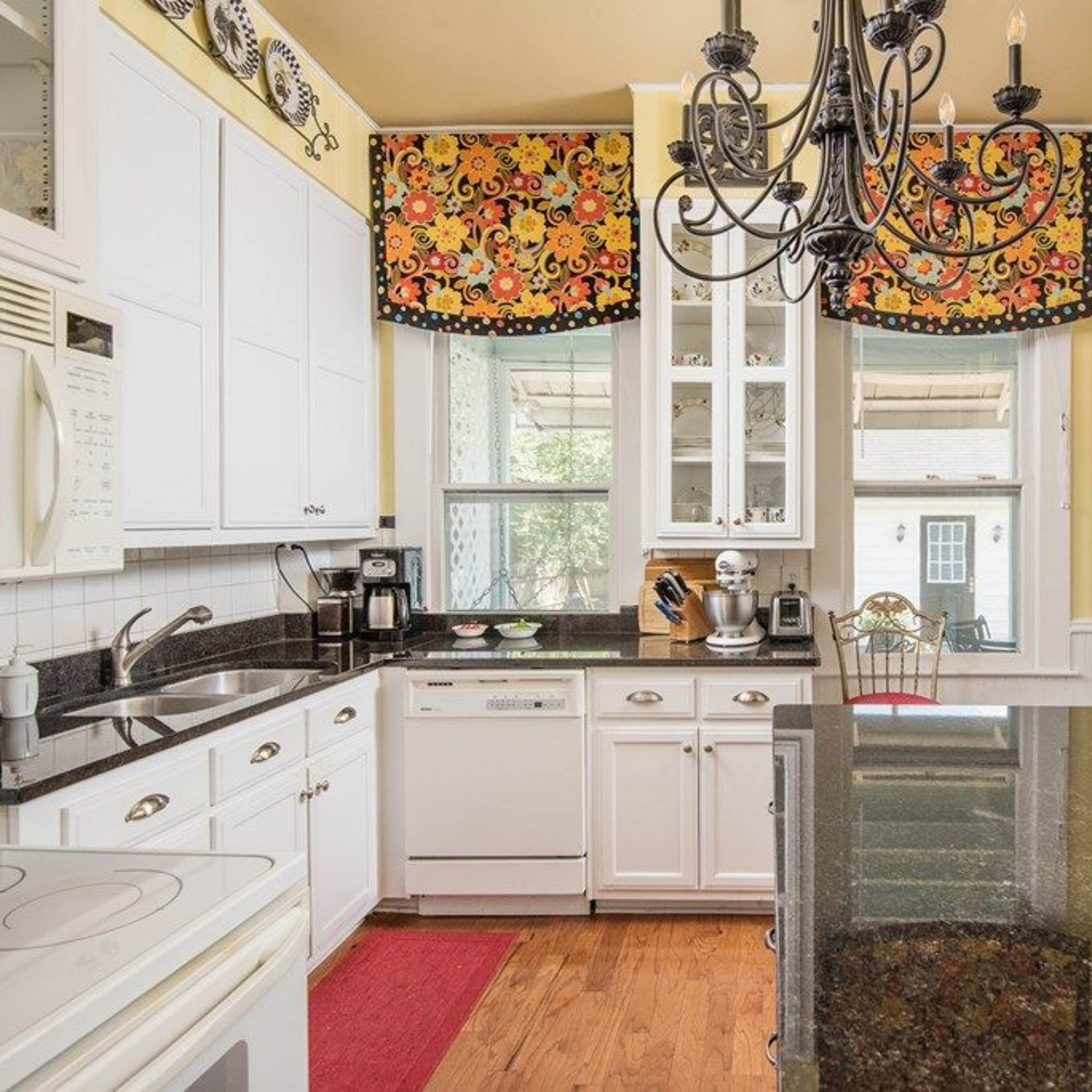 The kitchen features white cabinetry, a black countertop, and colorful patterned window treatments.