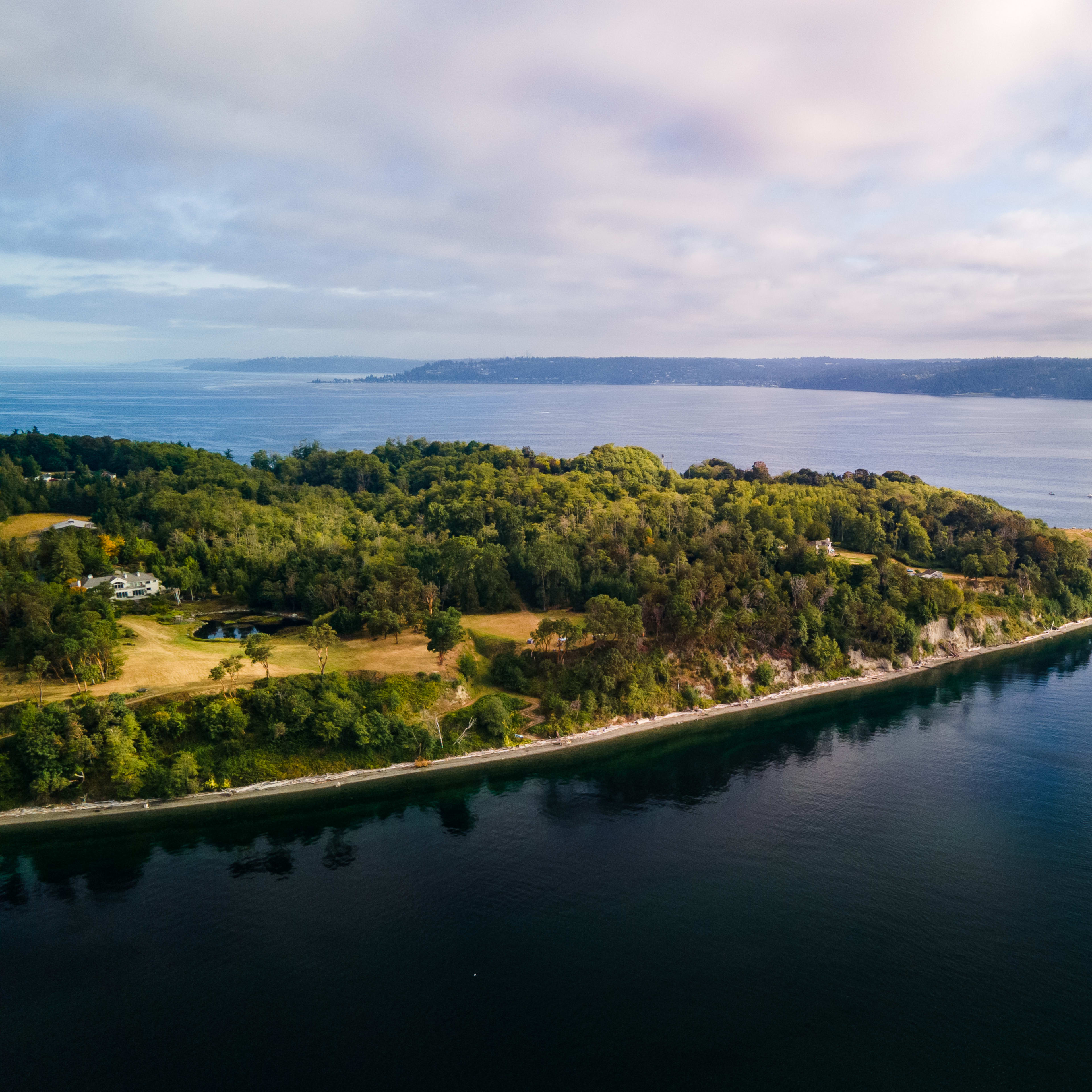 An aerial view of a lush, green island bordered by calm waters and distant hills.