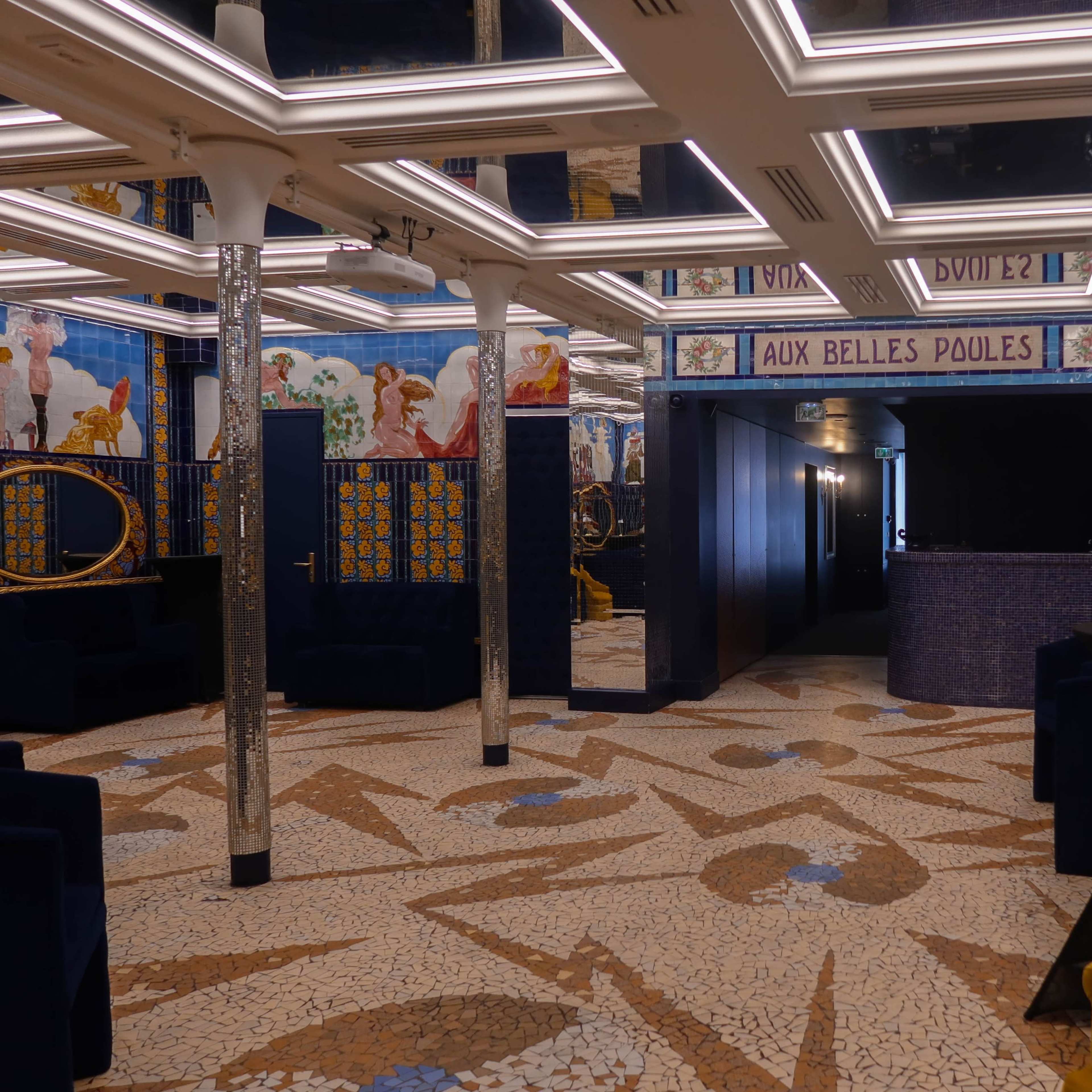 A stylish interior of a tiled room with decorative walls, two mirrors, and distinct seating areas.