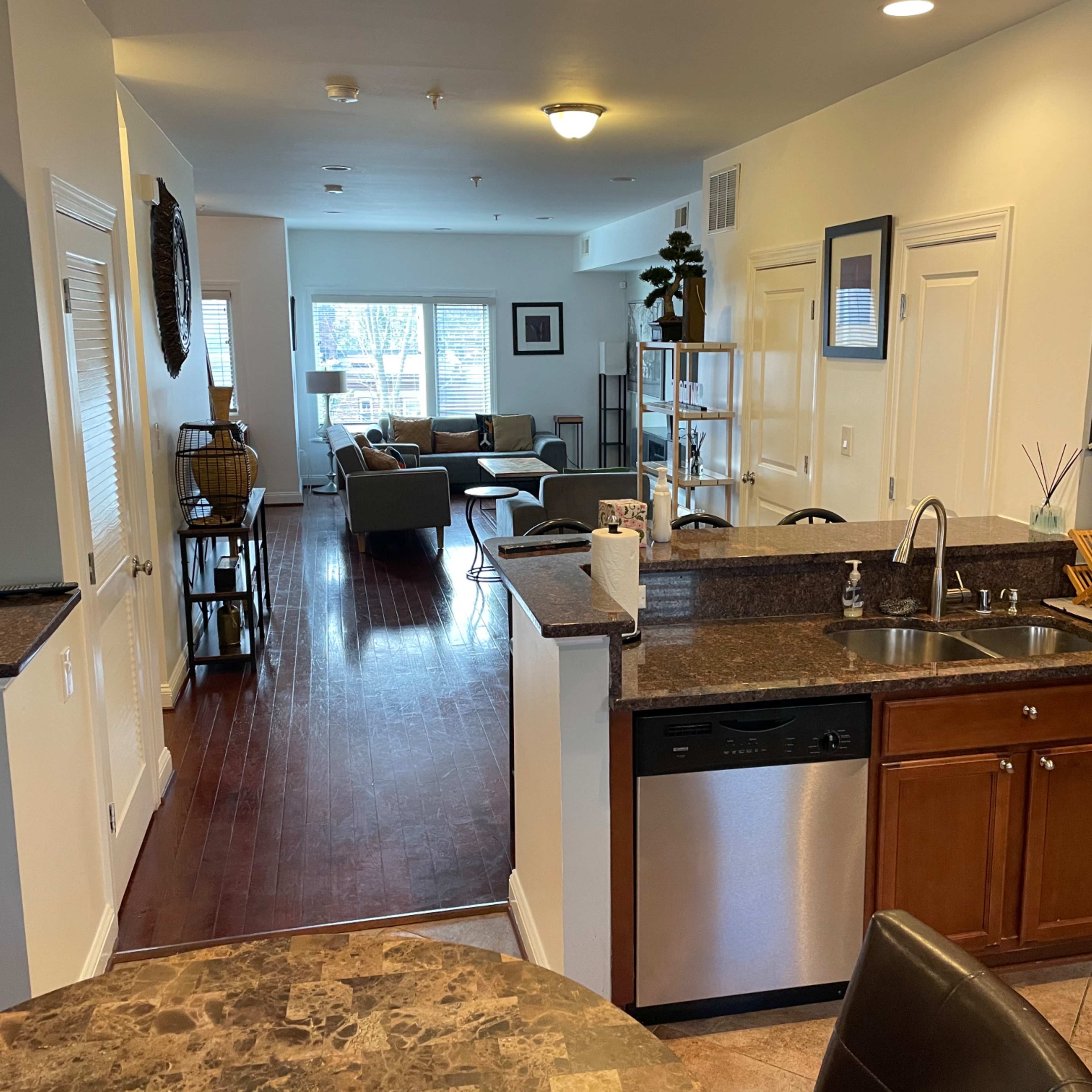 A bright, open-concept kitchen that flows into a living area with large windows and contemporary furnishings.
