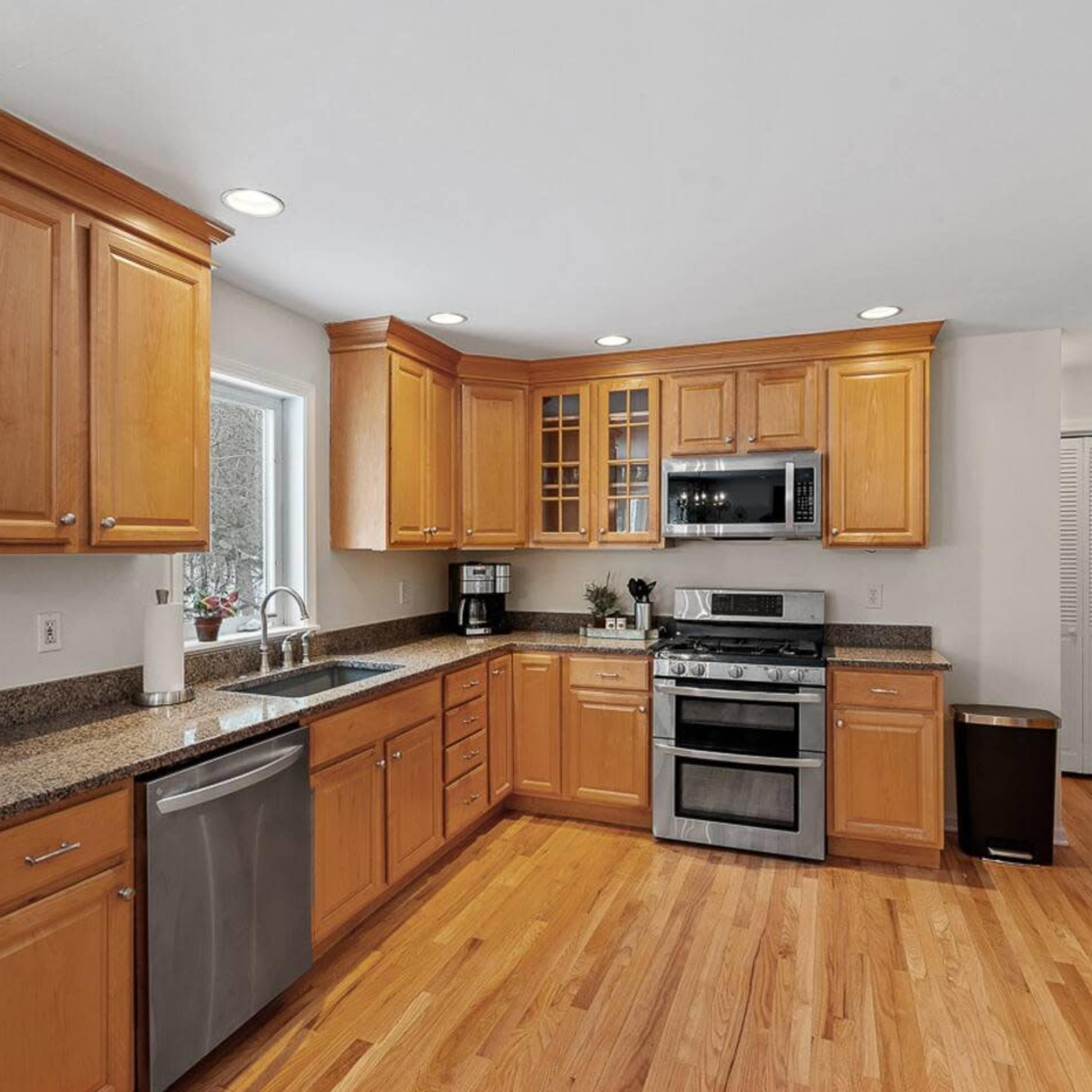 The kitchen features wooden cabinetry, granite countertops, stainless steel appliances, and hardwood flooring.