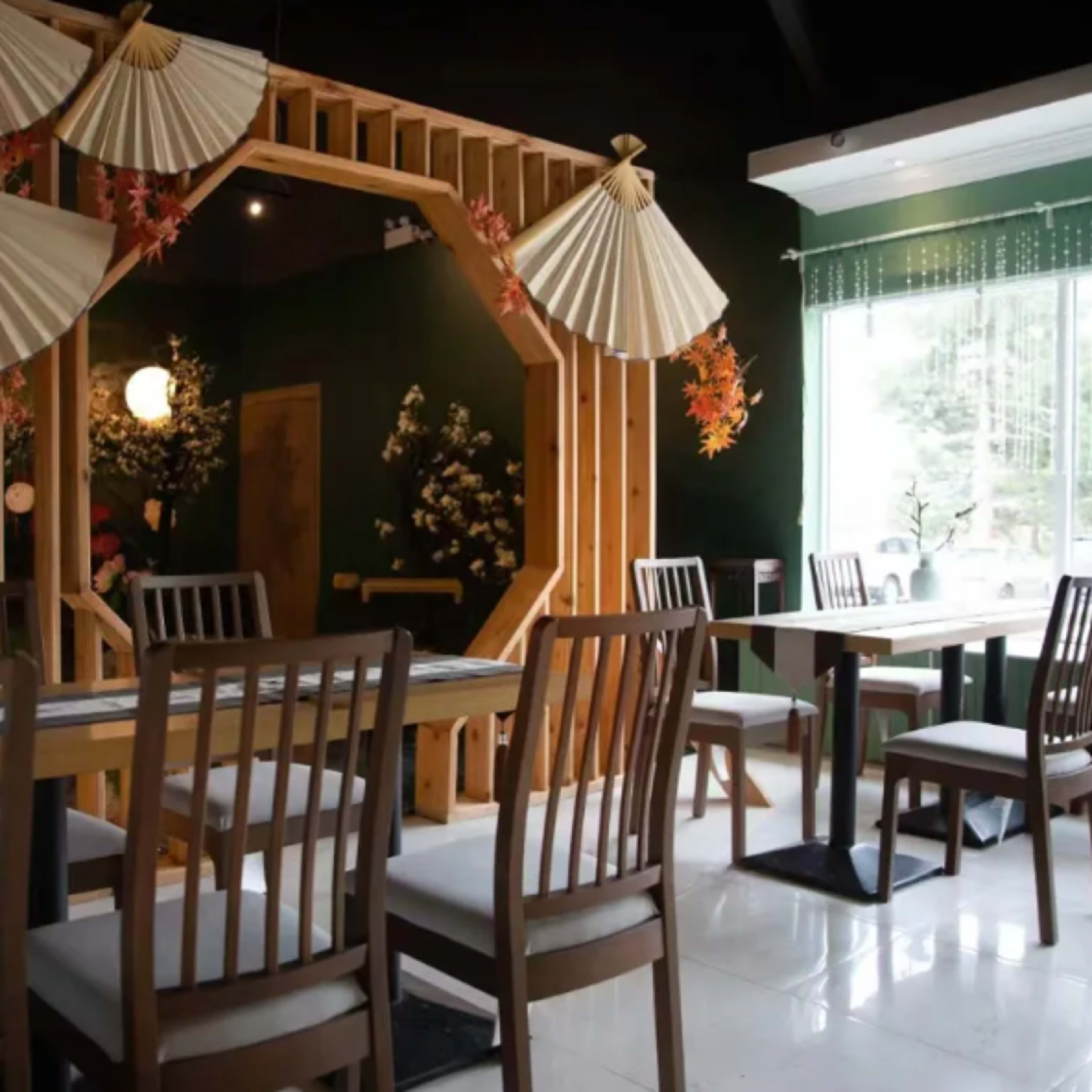 A minimalist dining area features a wooden table surrounded by chairs and decorative fans hanging on the walls.