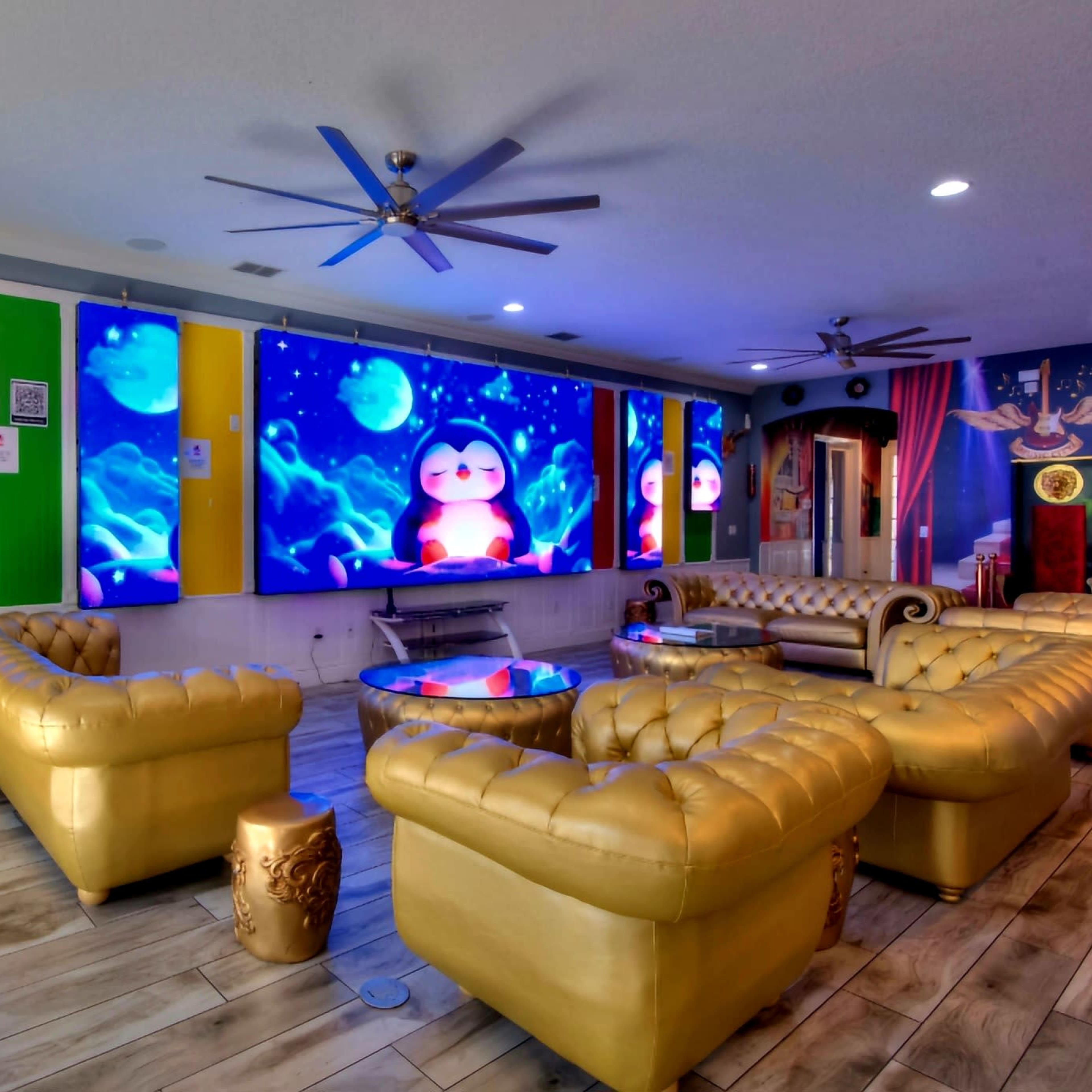 The scene shows a brightly lit lounge area featuring golden couches, large colorful wall displays, and a guitar leaning against the wall.