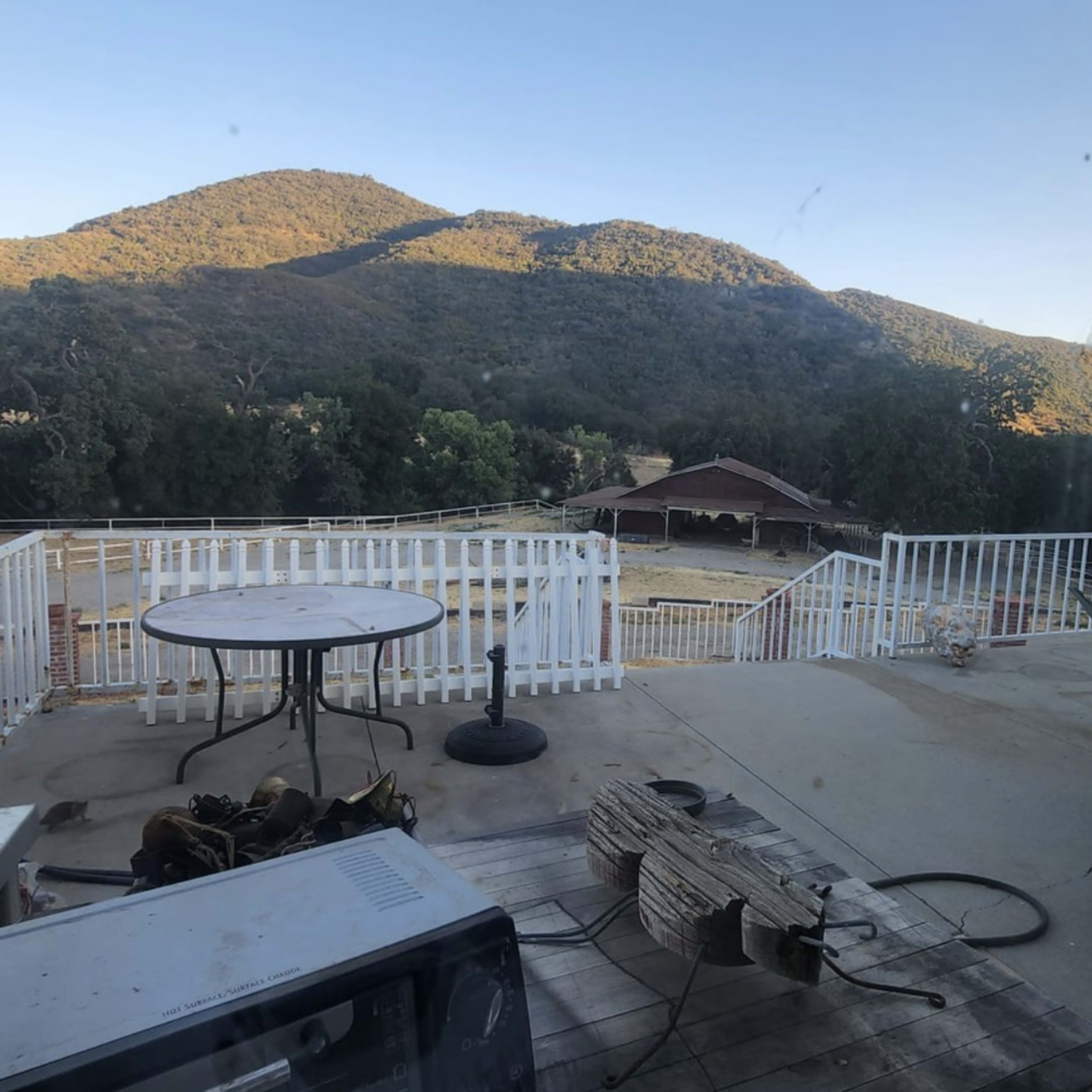 A view from a deck overlooking a mountainous landscape with a barn in the distance.