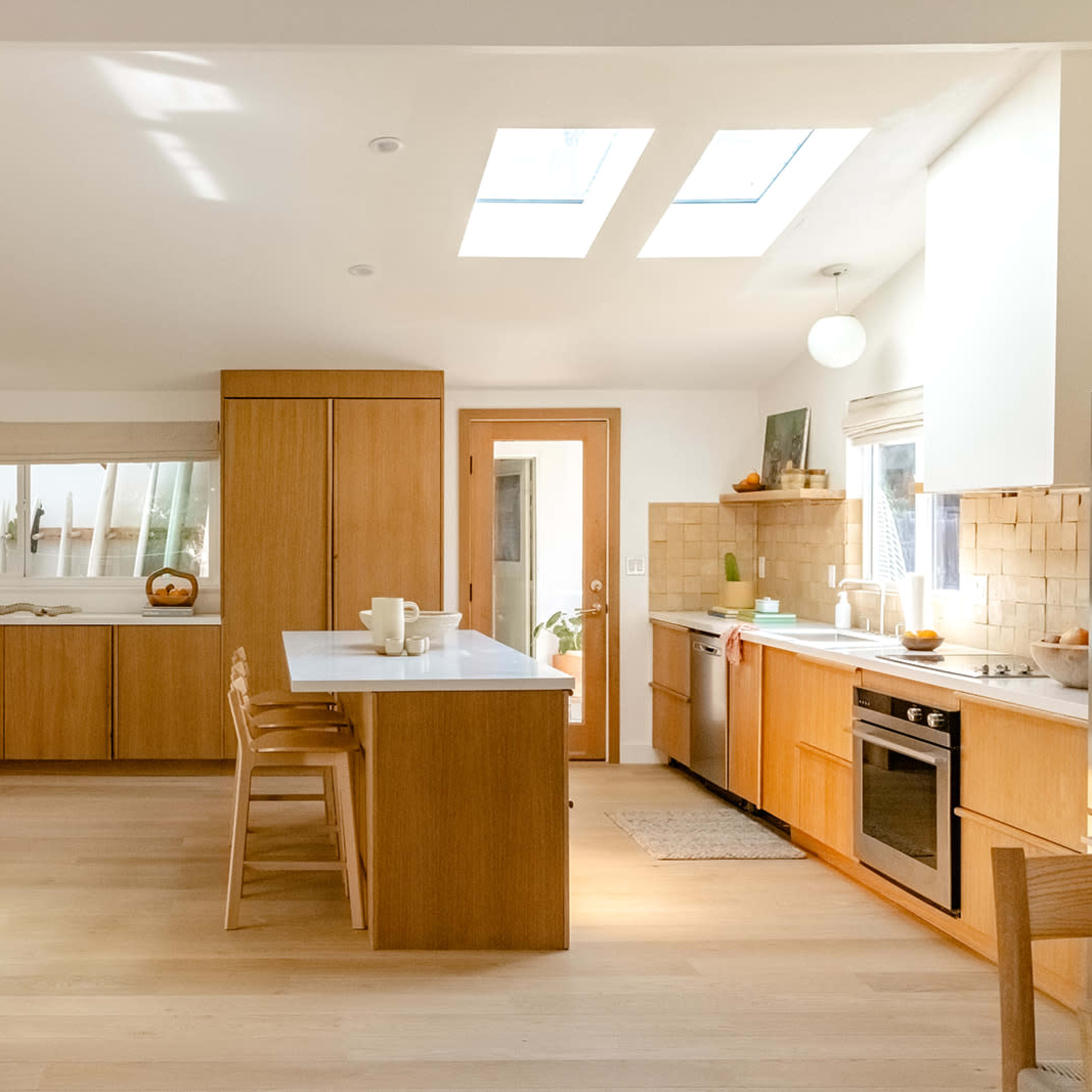 A modern kitchen featuring wooden cabinetry, a central island, and large skylights providing natural light.