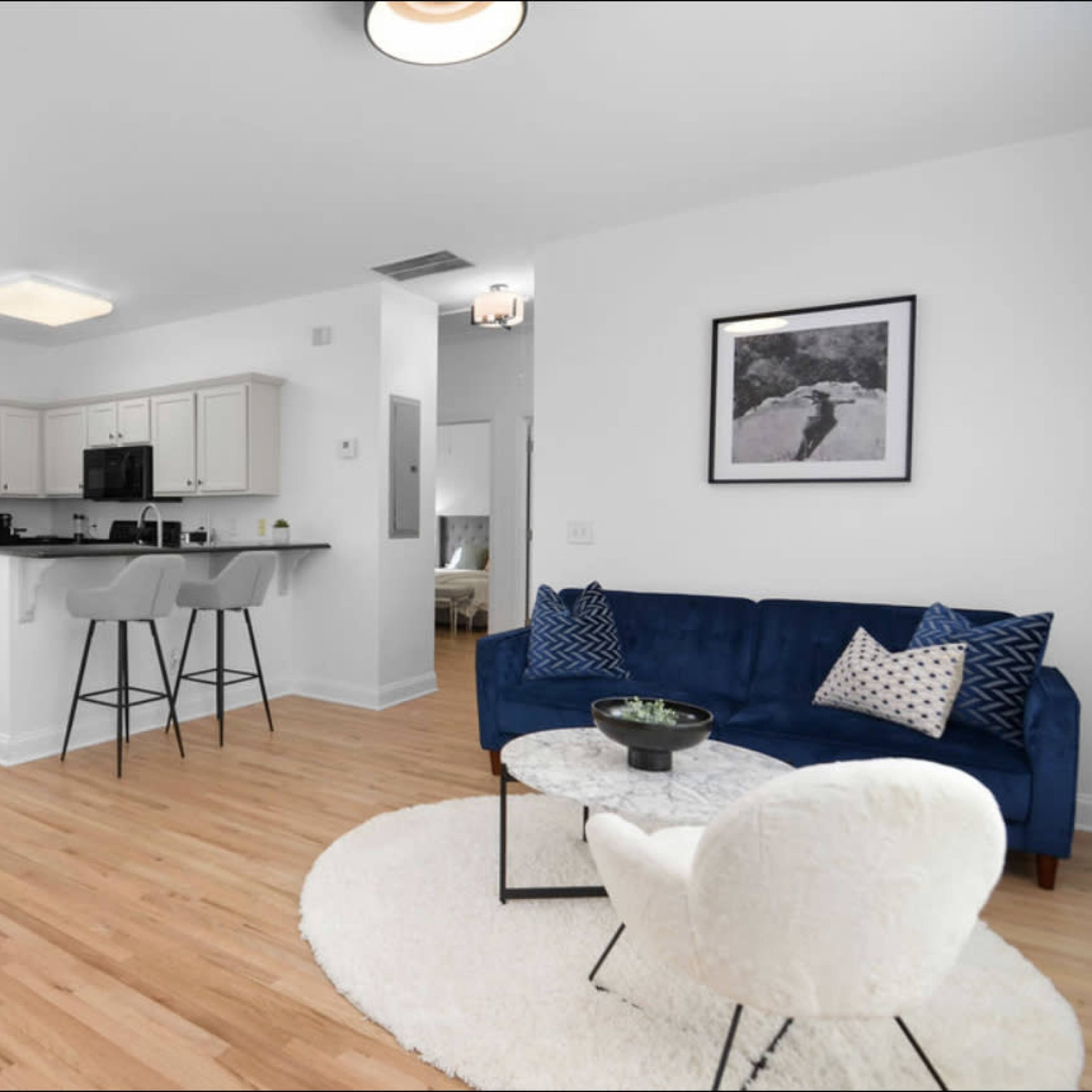 A modern, open-concept living area with a kitchen bar, stylish furniture, and a dining table.