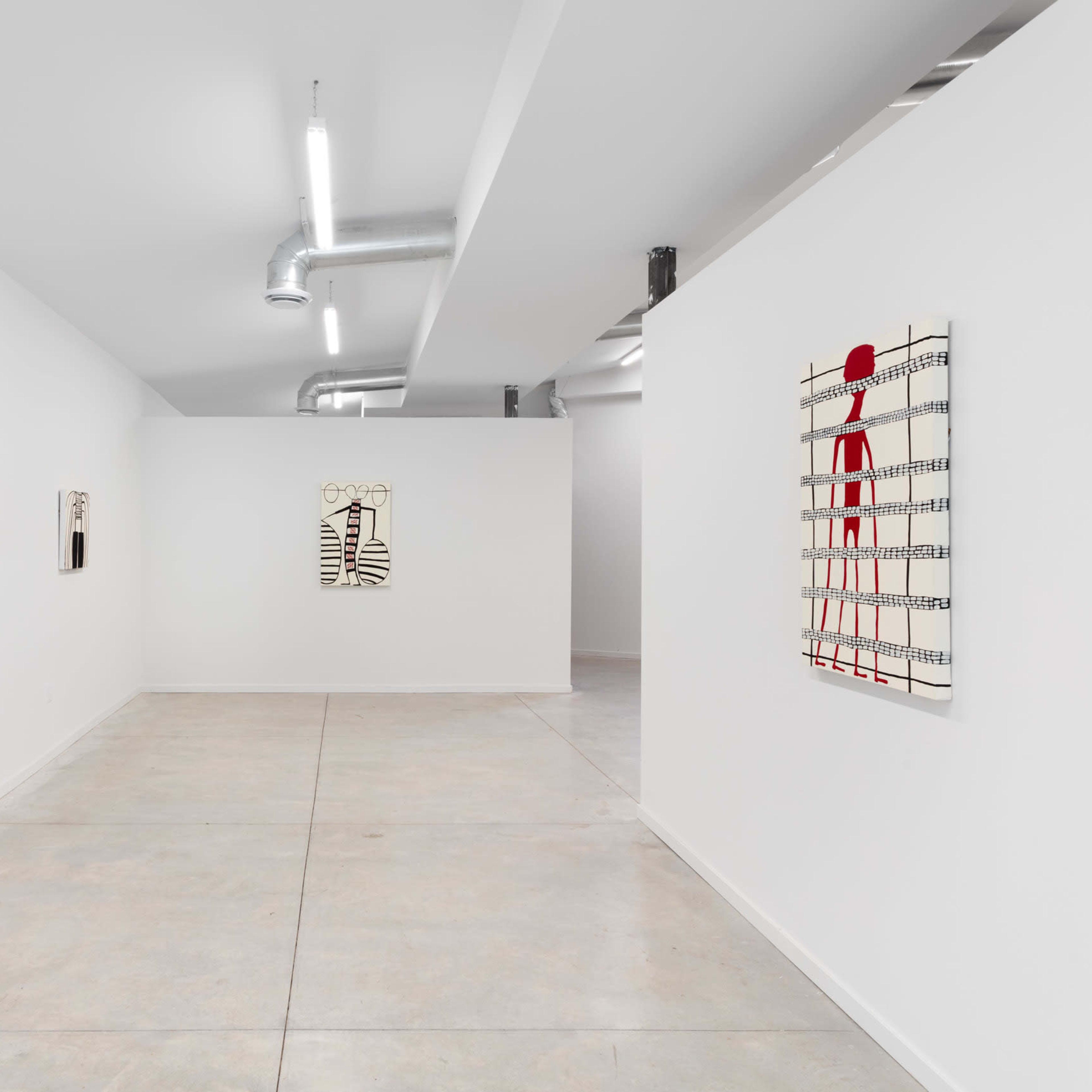 An interior art gallery with white walls featuring several abstract paintings displayed on the walls.