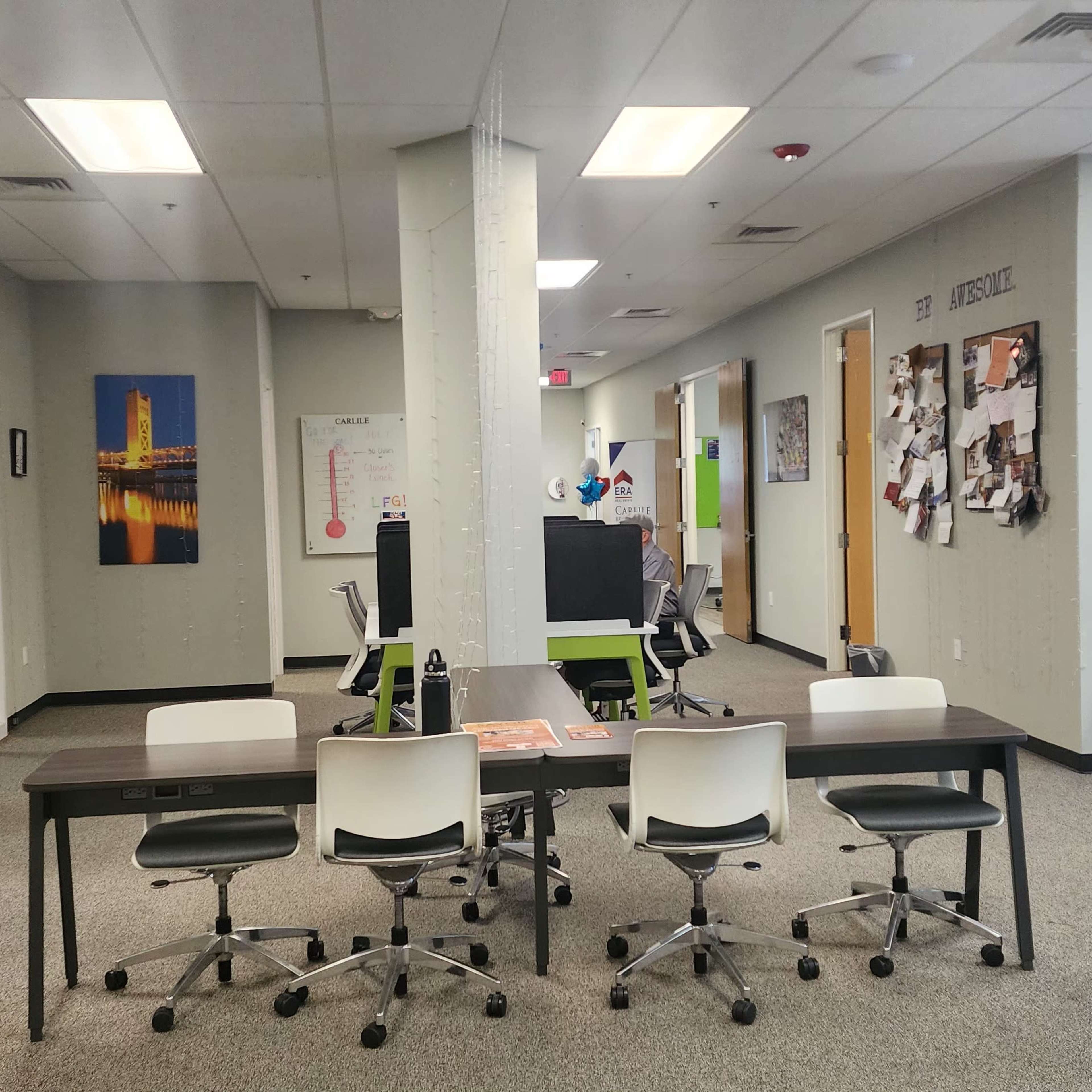 A modern office space with several workstations, light-colored walls, and decorative artwork.