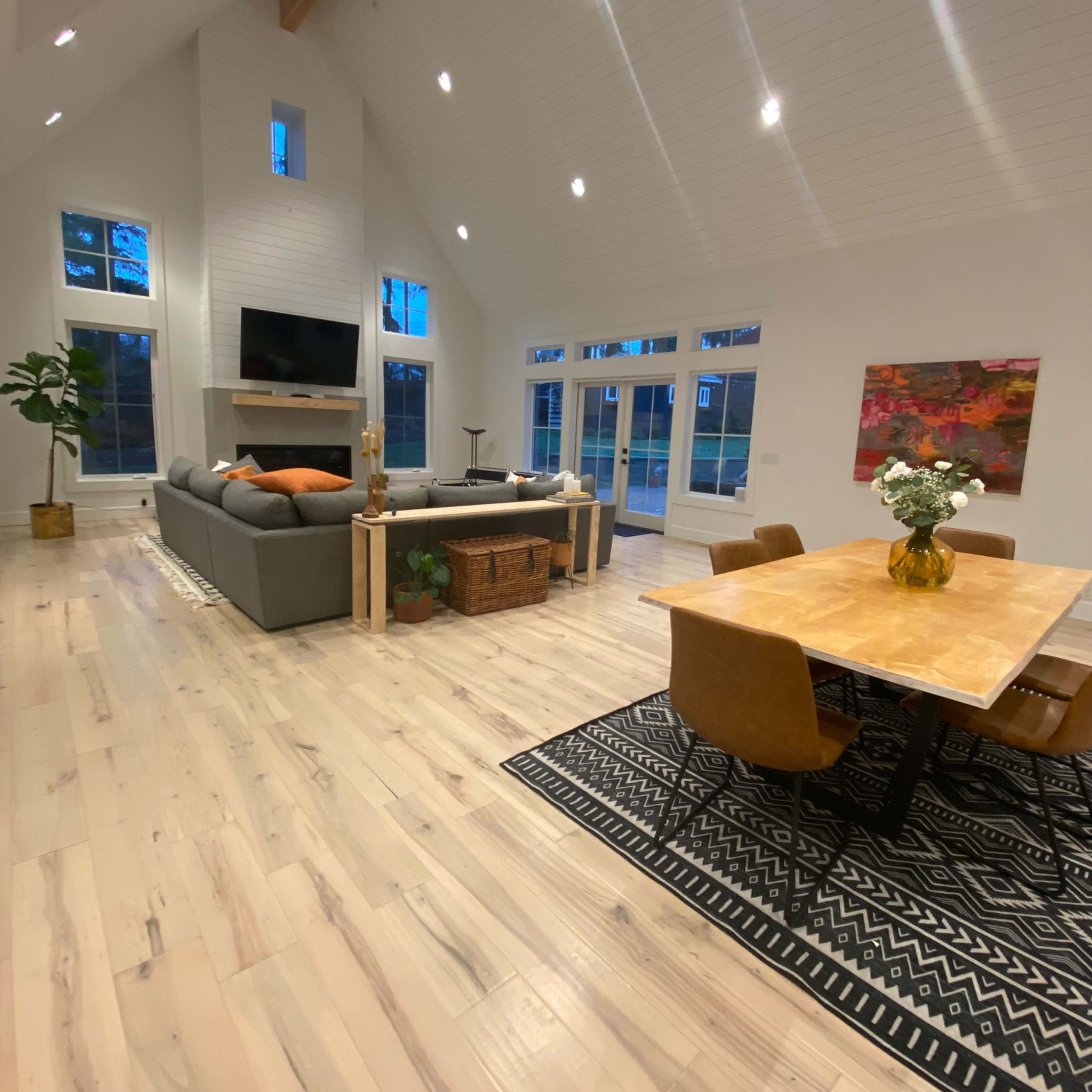 A spacious modern living area with a couch, dining table, and large windows allowing natural light to fill the room.