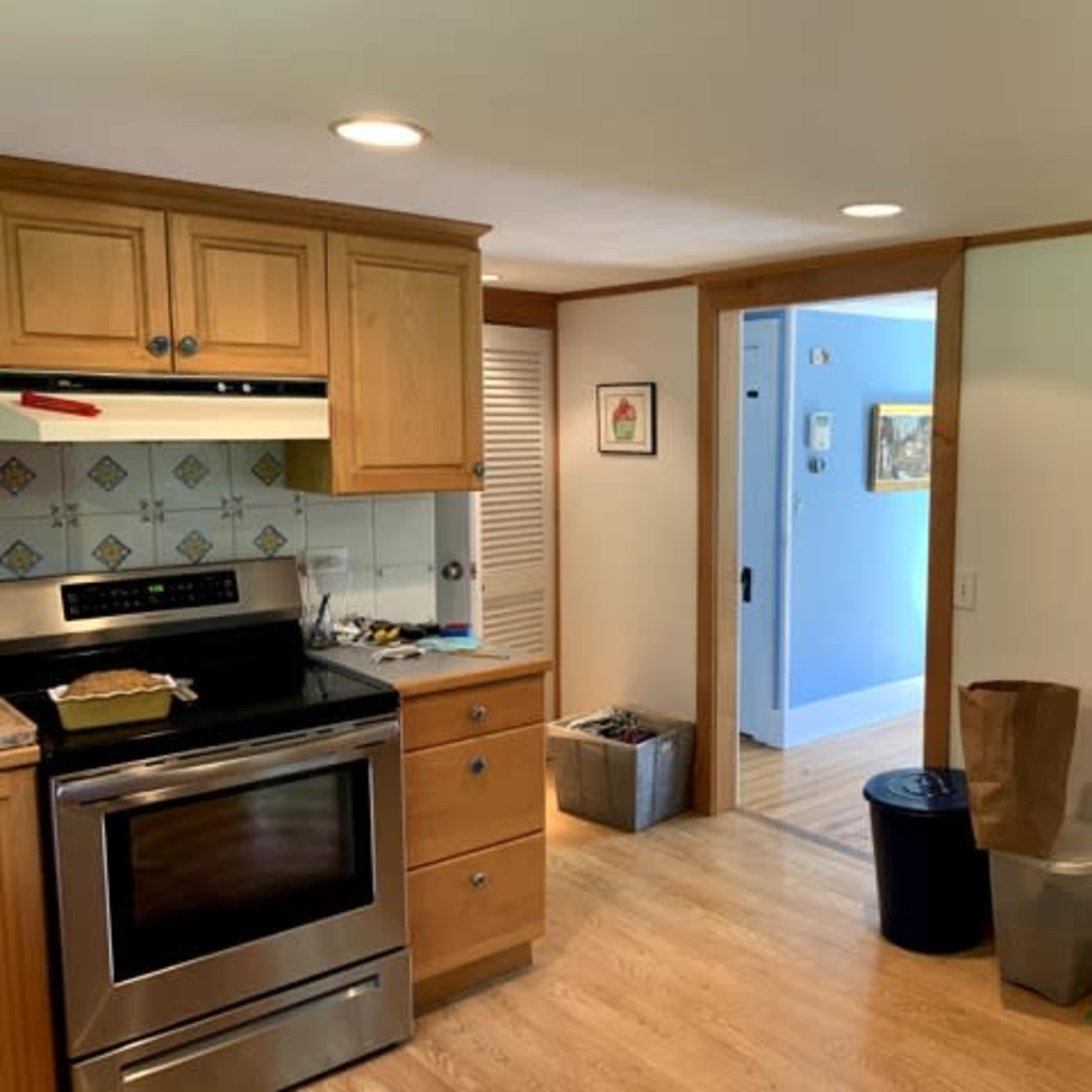A kitchen features wooden cabinetry, a stainless steel stove, and a doorway leading to a blue wall room.