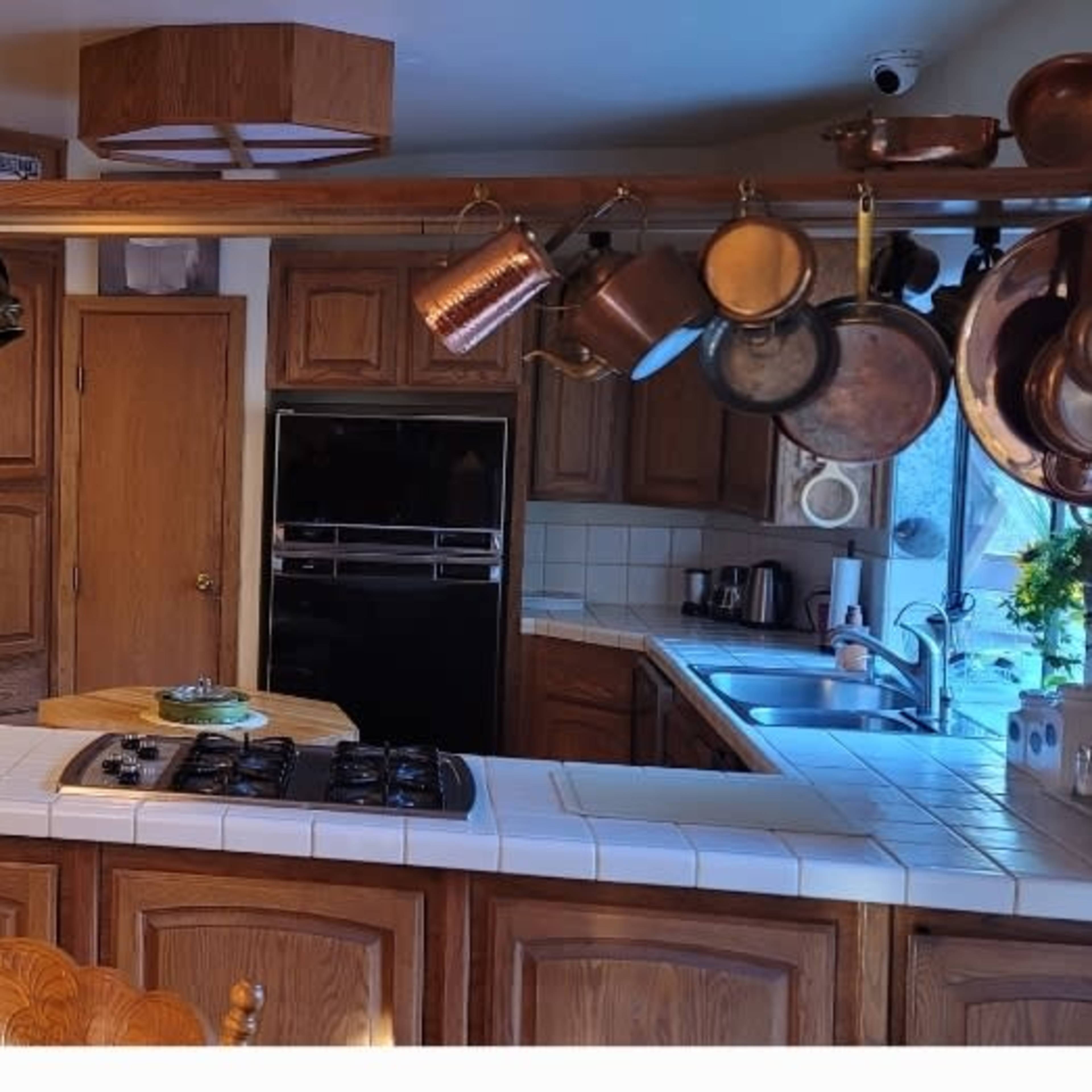 A wooden kitchen with a central island, equipped with a stove, and featuring cabinets filled with dishware.