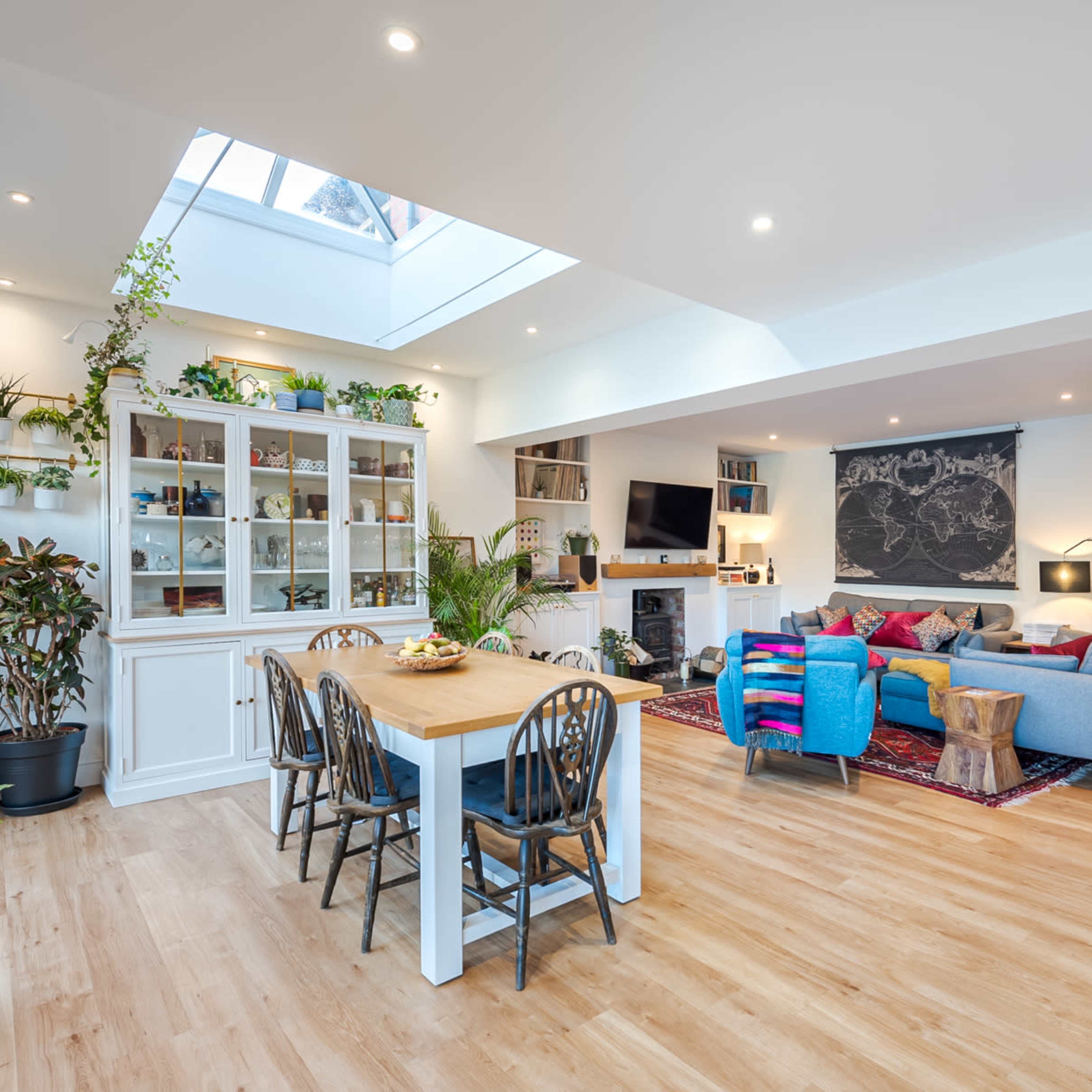 A bright, open-plan living and dining area adorned with various potted plants and modern furnishings.
