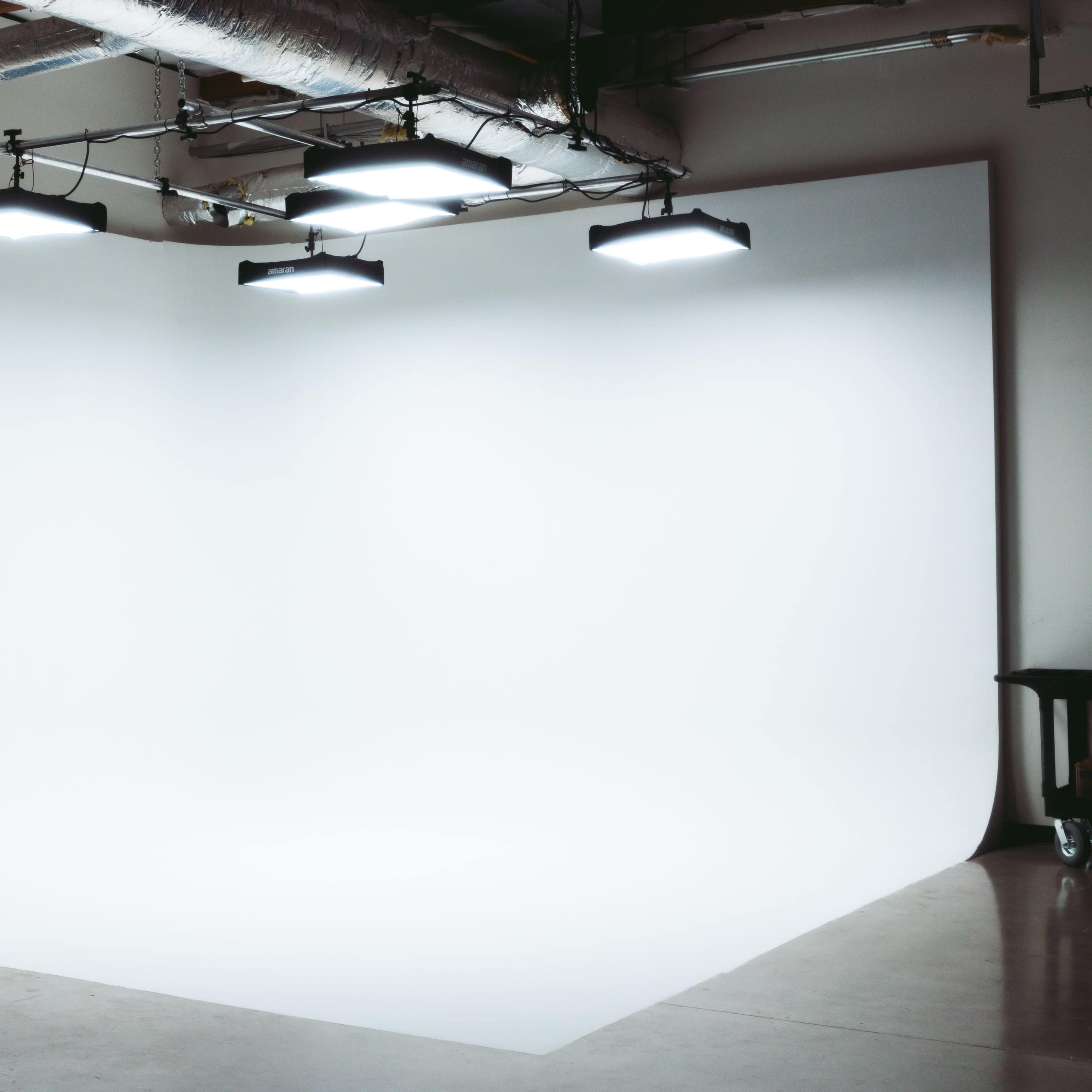 A minimalistic studio space with a seamless white backdrop and overhead lighting.