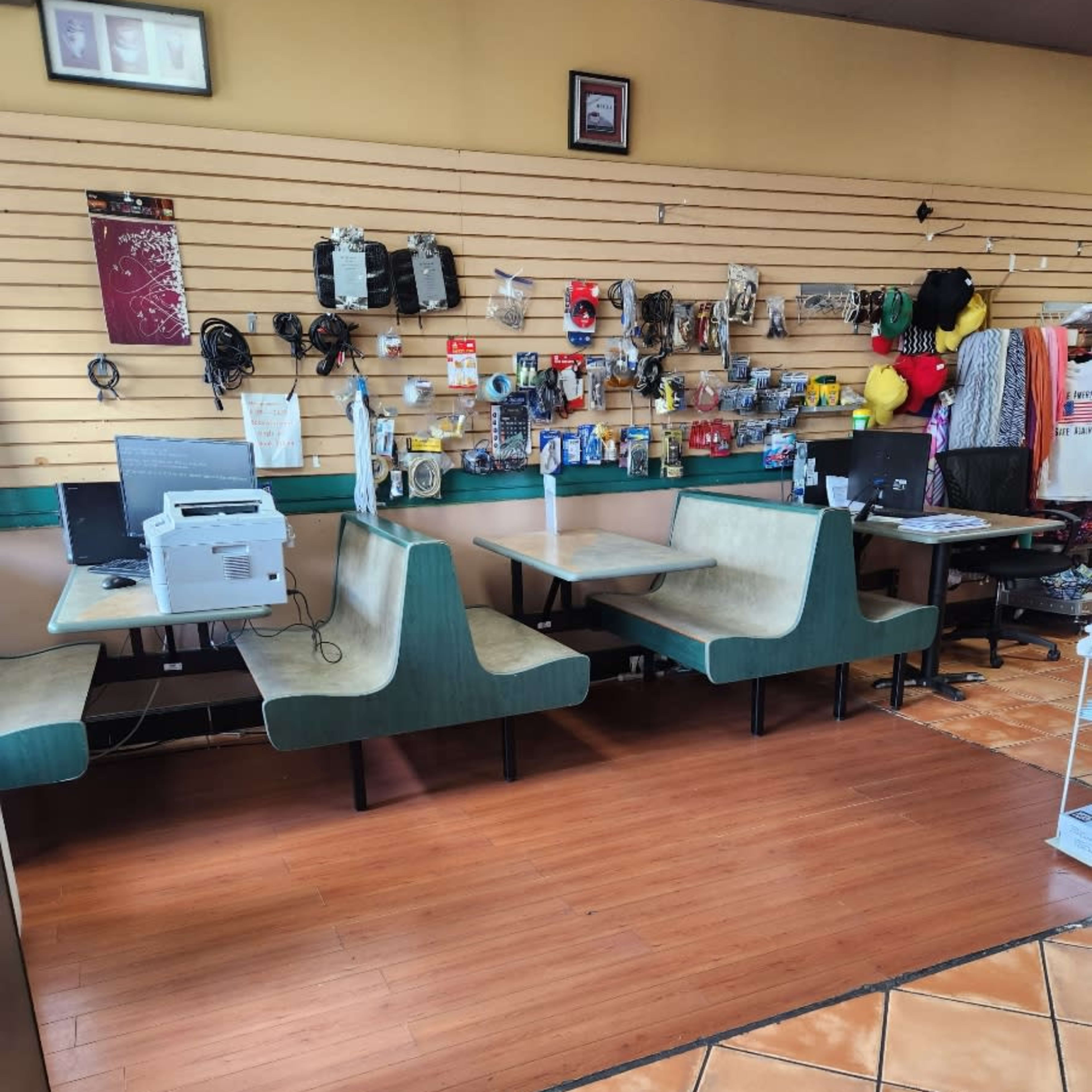 A room with two booths and tables, a computer station, and various items displayed on a wall shelf.