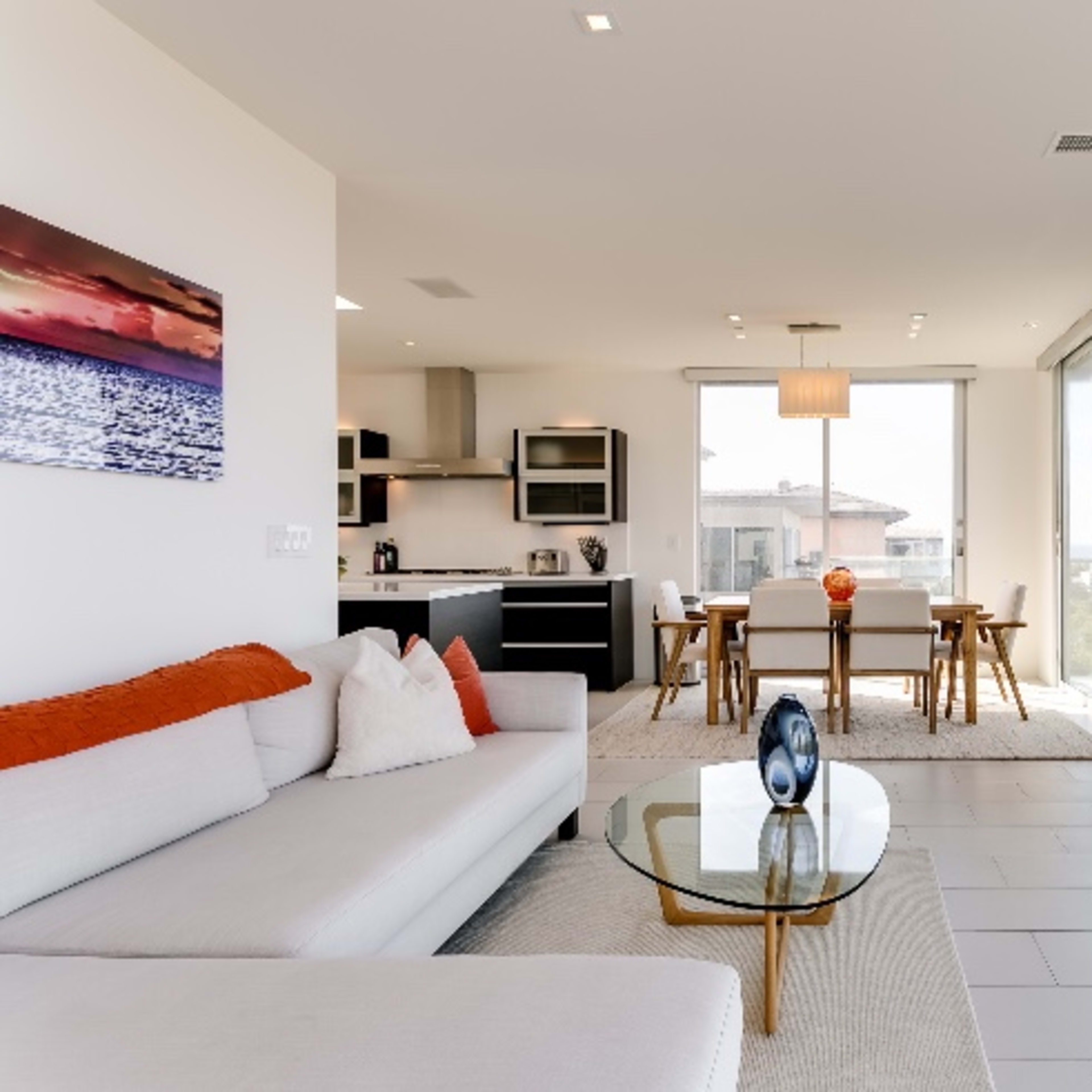 A modern, open-concept living space with a sectional sofa, dining area, and large windows overlooking a landscape.