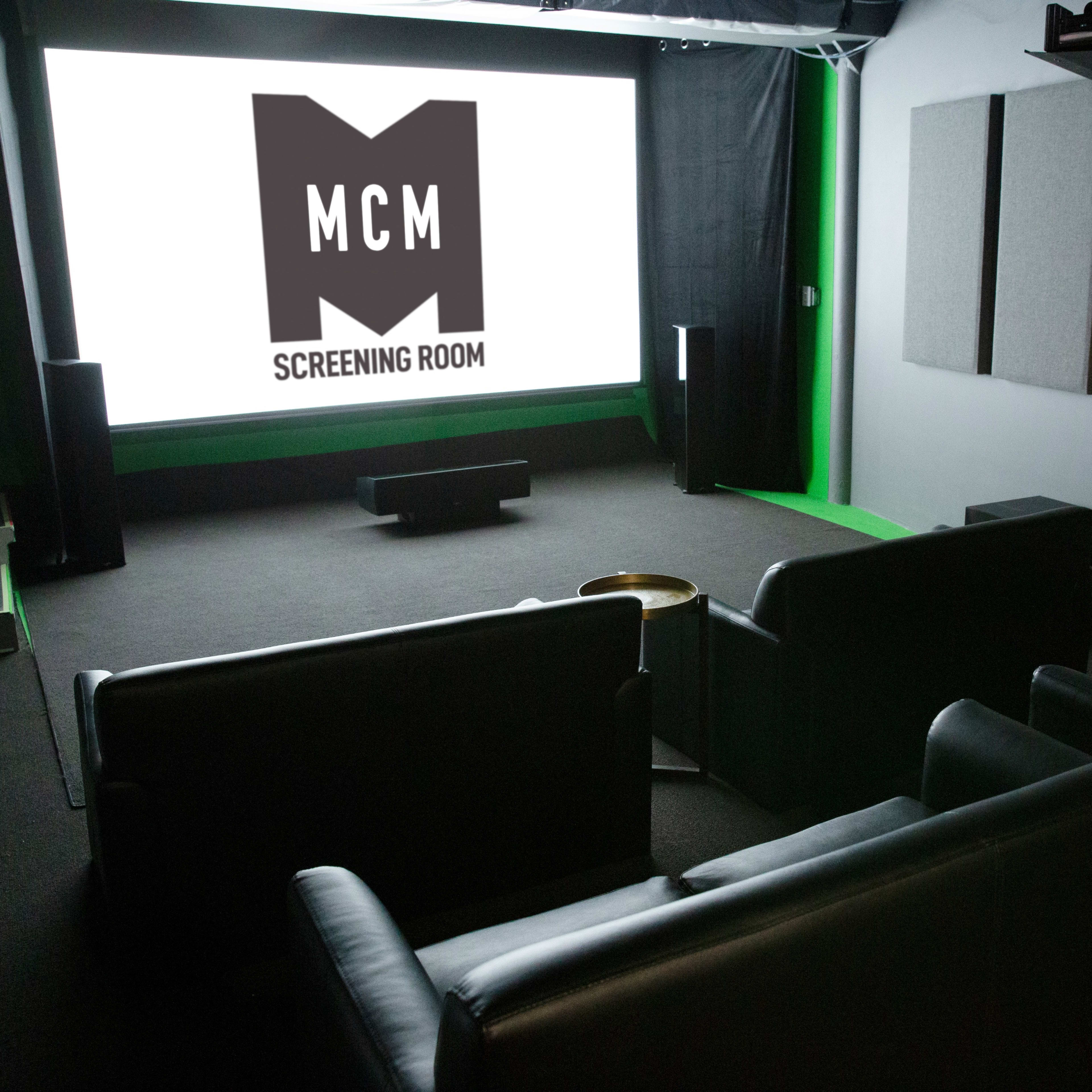 A cozy screening room features dark seating in front of a large projection screen displaying the logo "MCM SCREENING ROOM."
