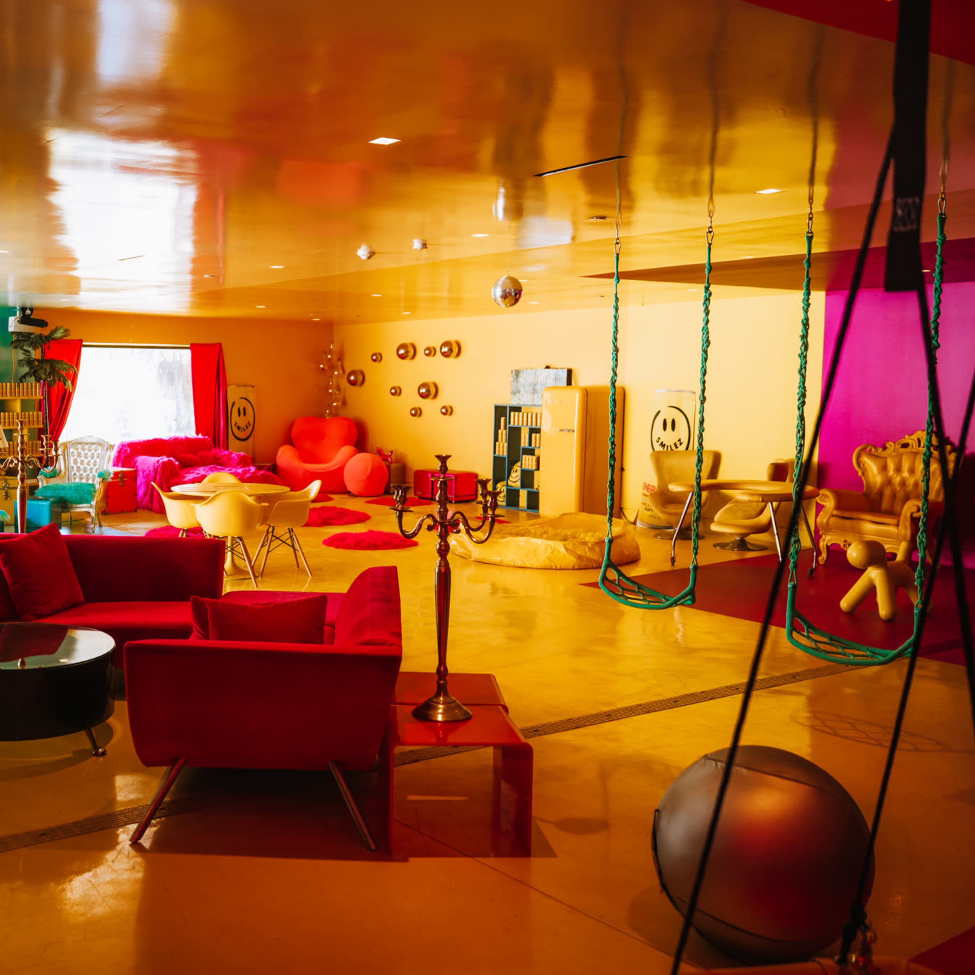 A brightly colored lounge area featuring various seating arrangements, vibrant walls, and playful décor elements.