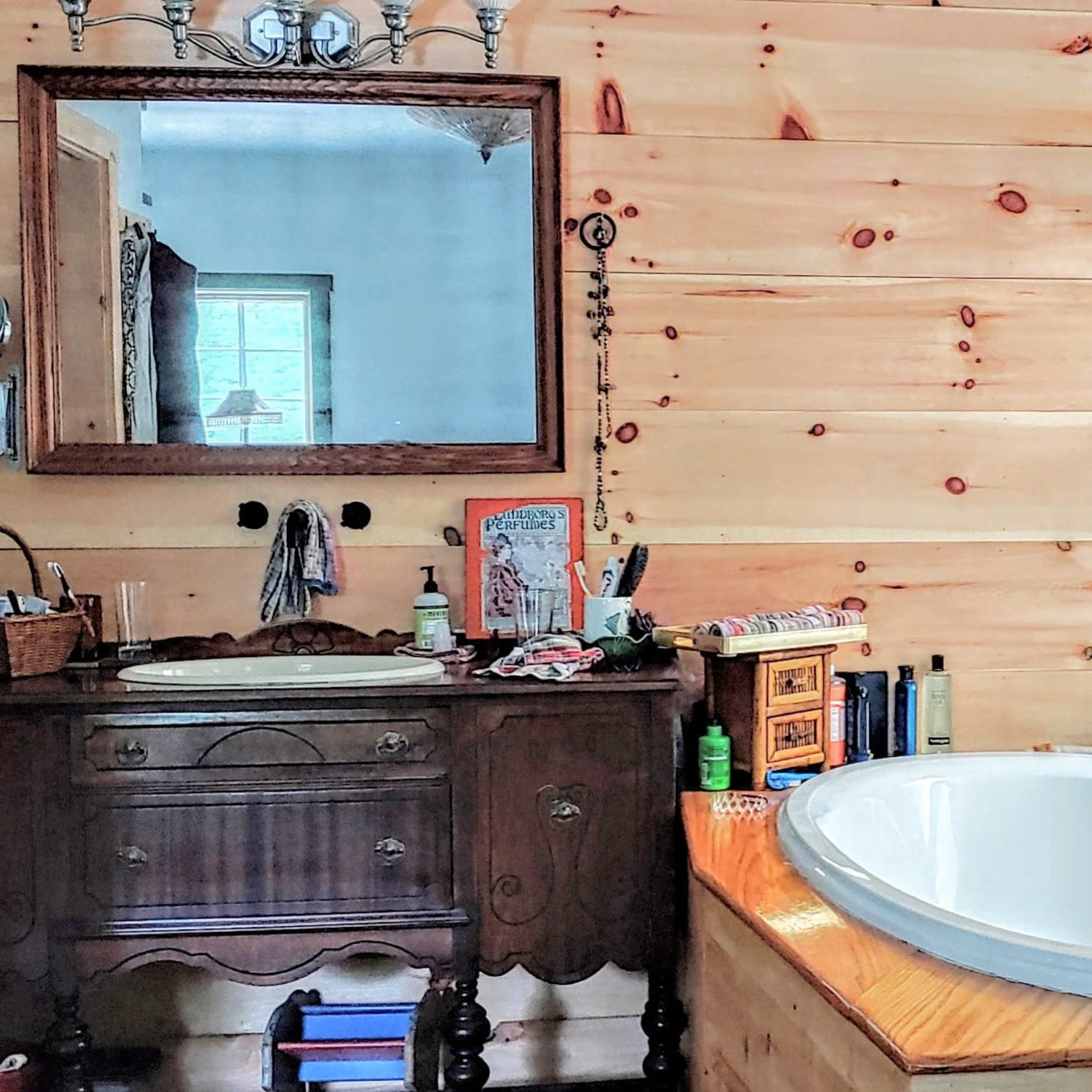 A bathroom with wooden walls, featuring a large bathtub, a double sink vanity, and a mirror above the sink.