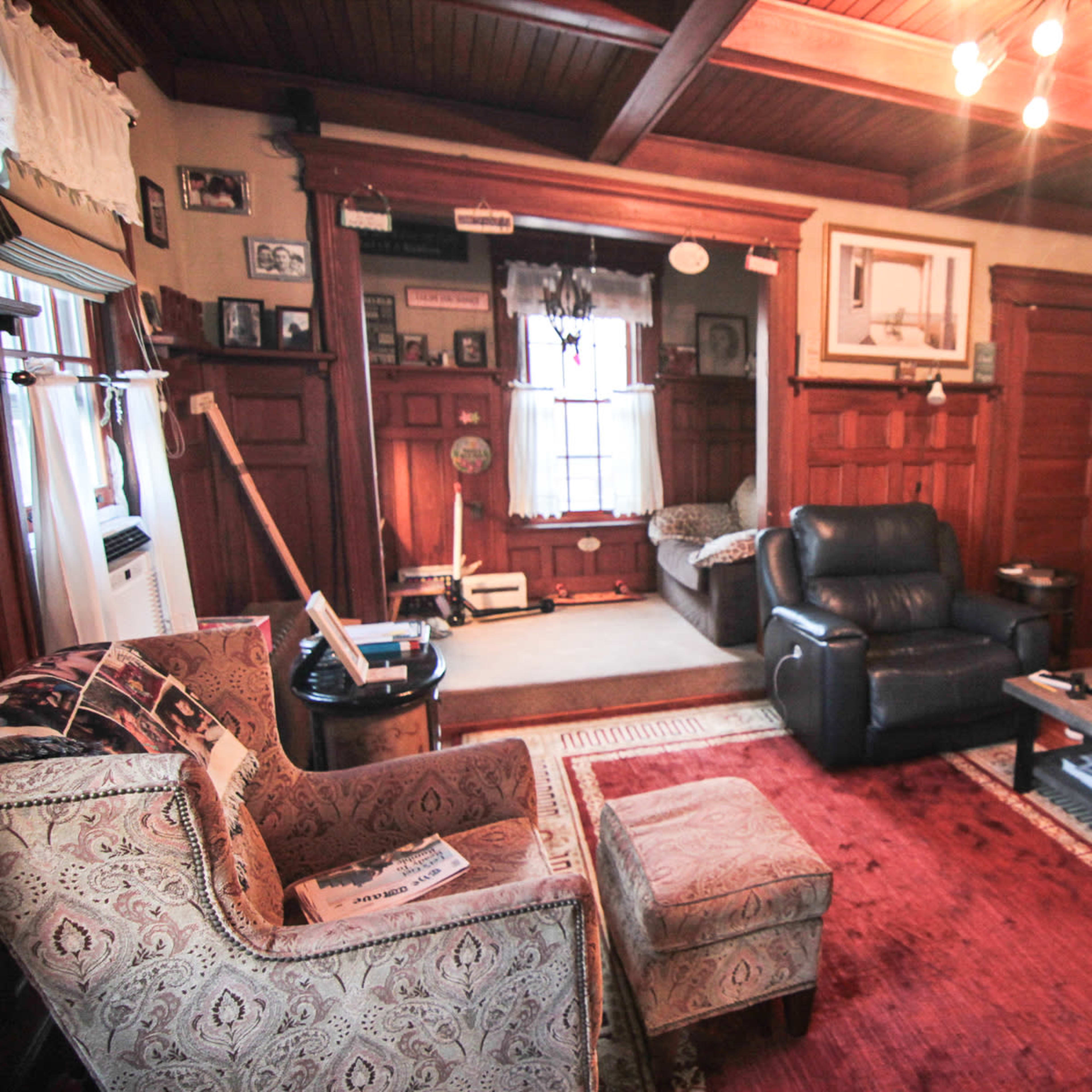 A living room with wooden paneling, two sofas, a coffee table, and various framed pictures on the walls.