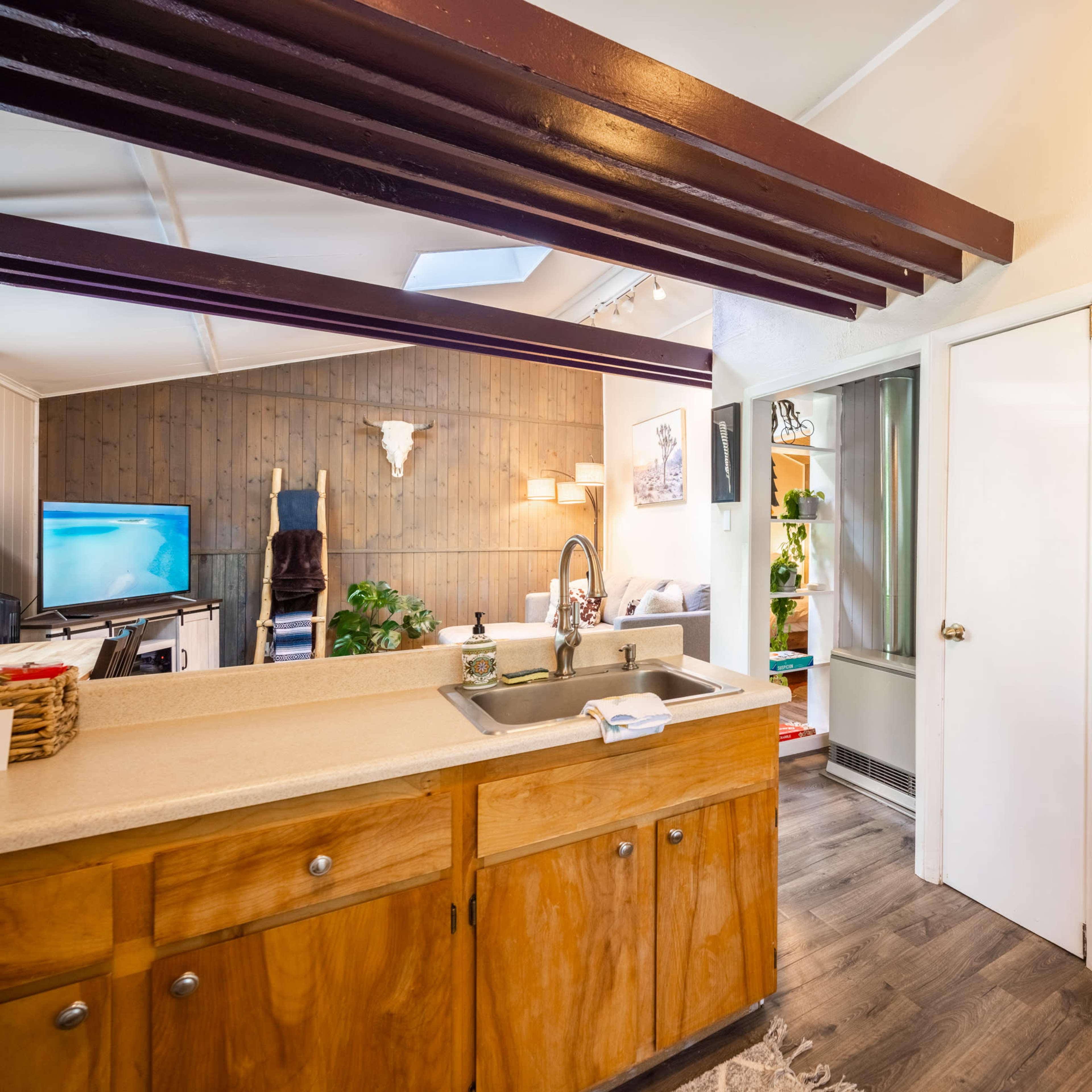 A kitchen area with a wooden countertop, a sink, and a doorway leading to a laundry space.
