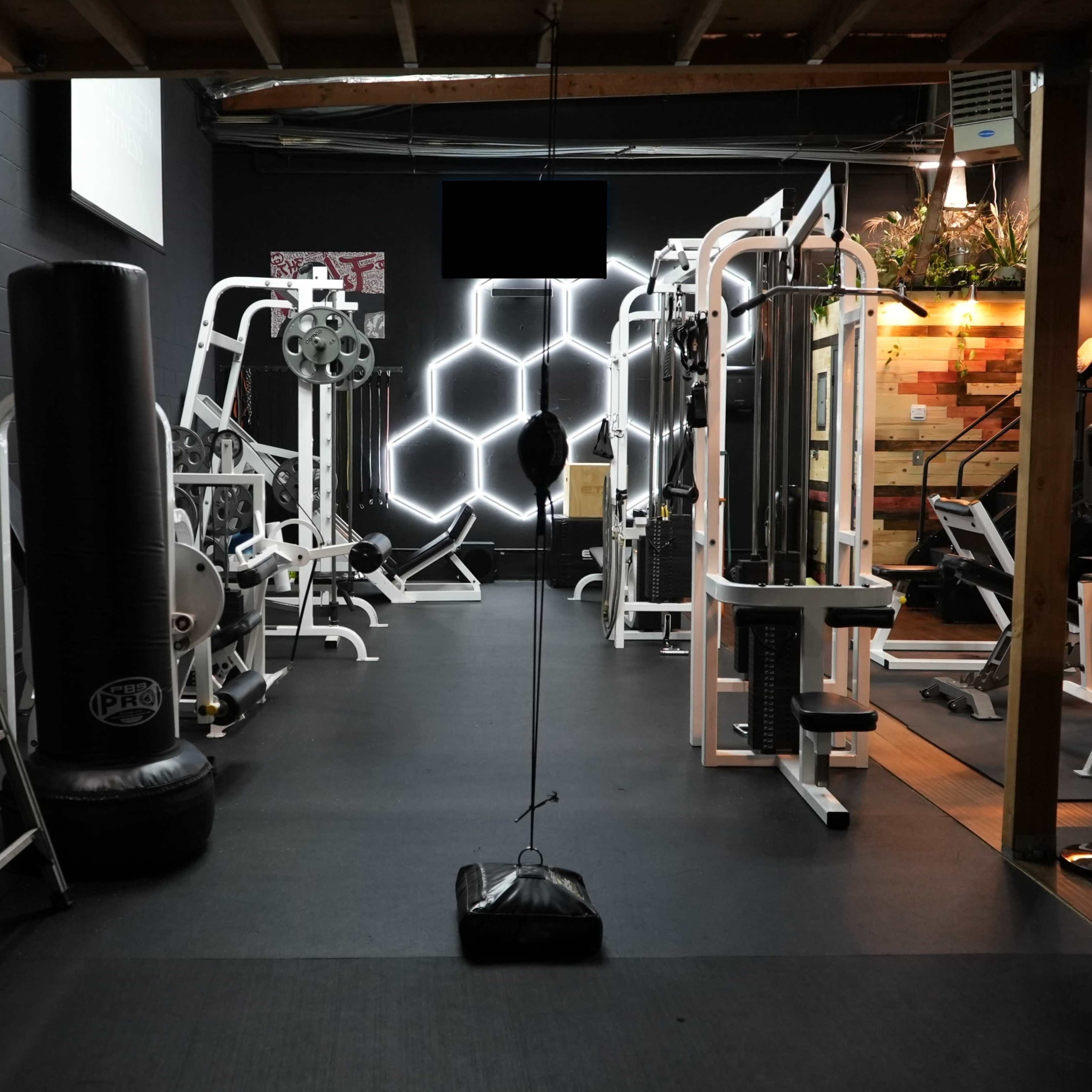 A gym interior with various exercise equipment, including a punching bag and weight machines, arranged in a well-lit space.