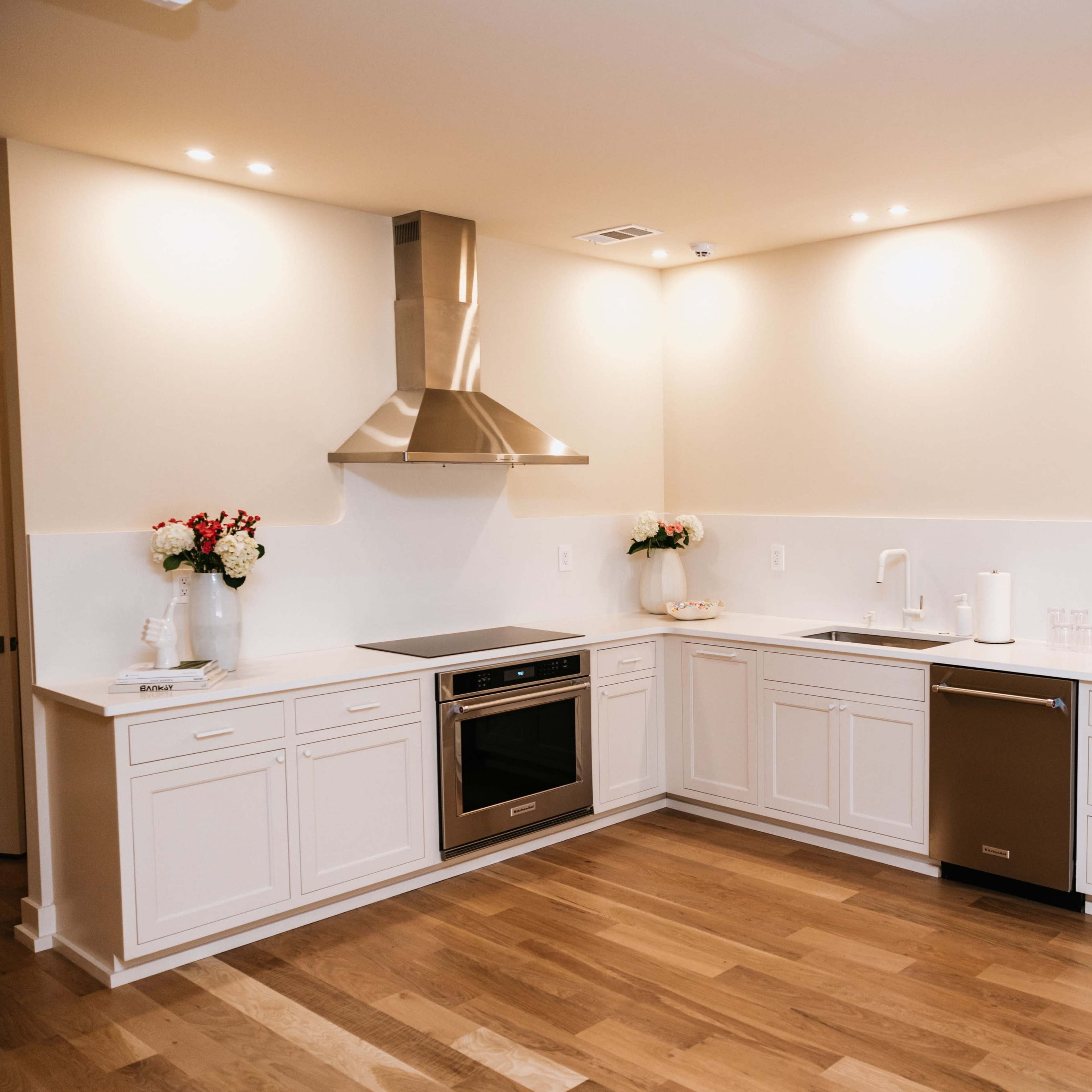 The kitchen features white cabinetry, stainless steel appliances, and a central island with a range hood overhead.