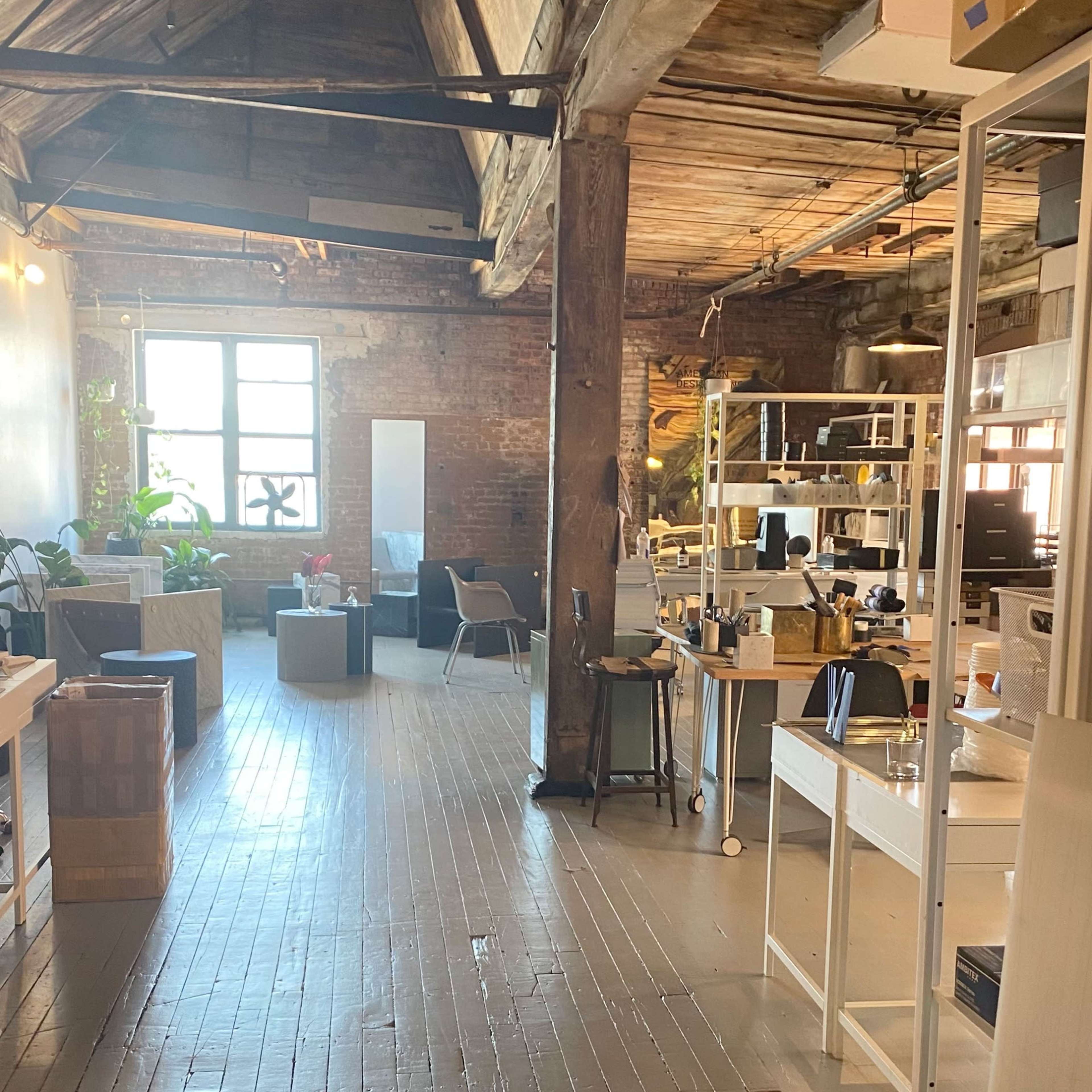 A spacious loft-style office with wooden beams, divided workstations, and various seating areas.