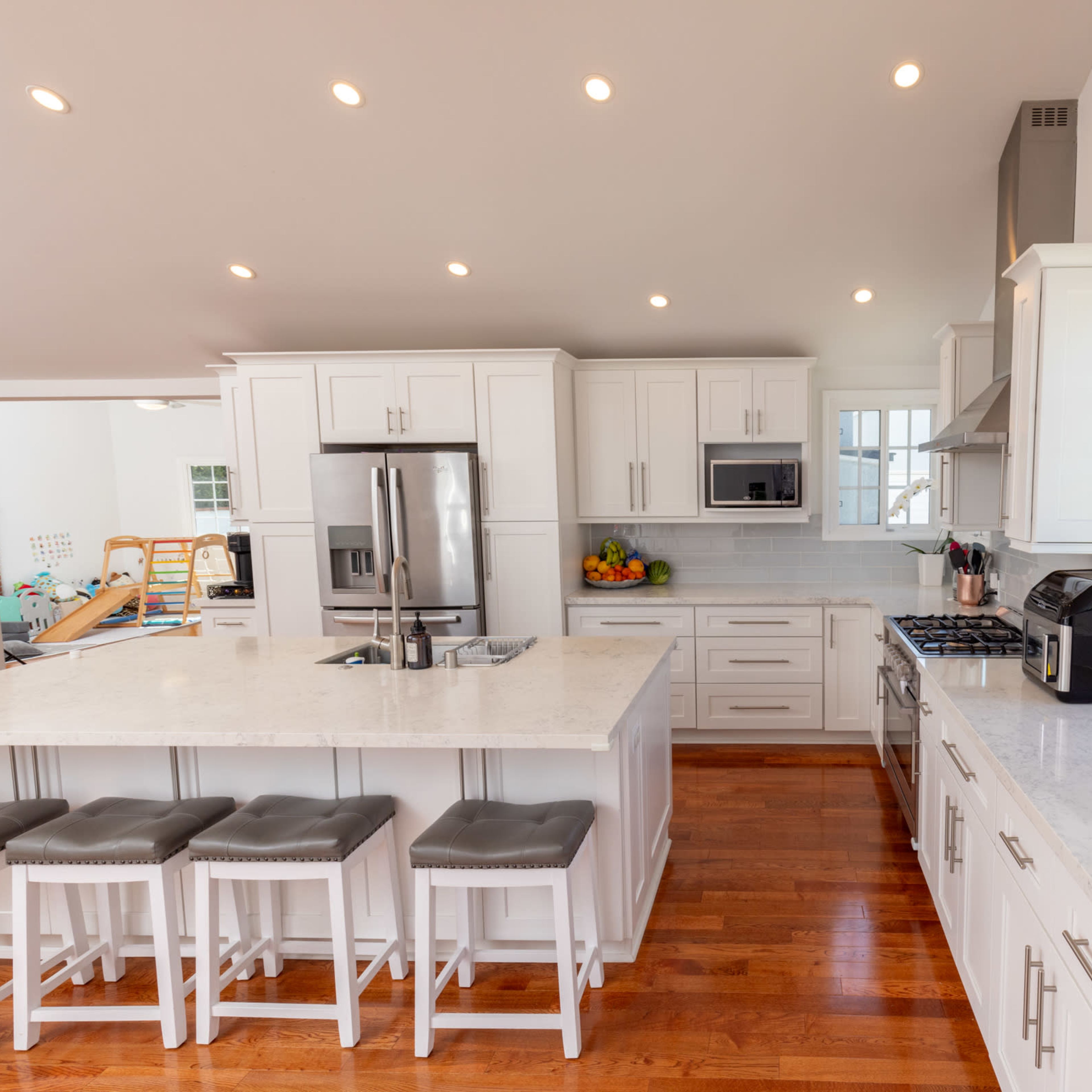 A modern kitchen with white cabinets, a large island, and stainless steel appliances.
