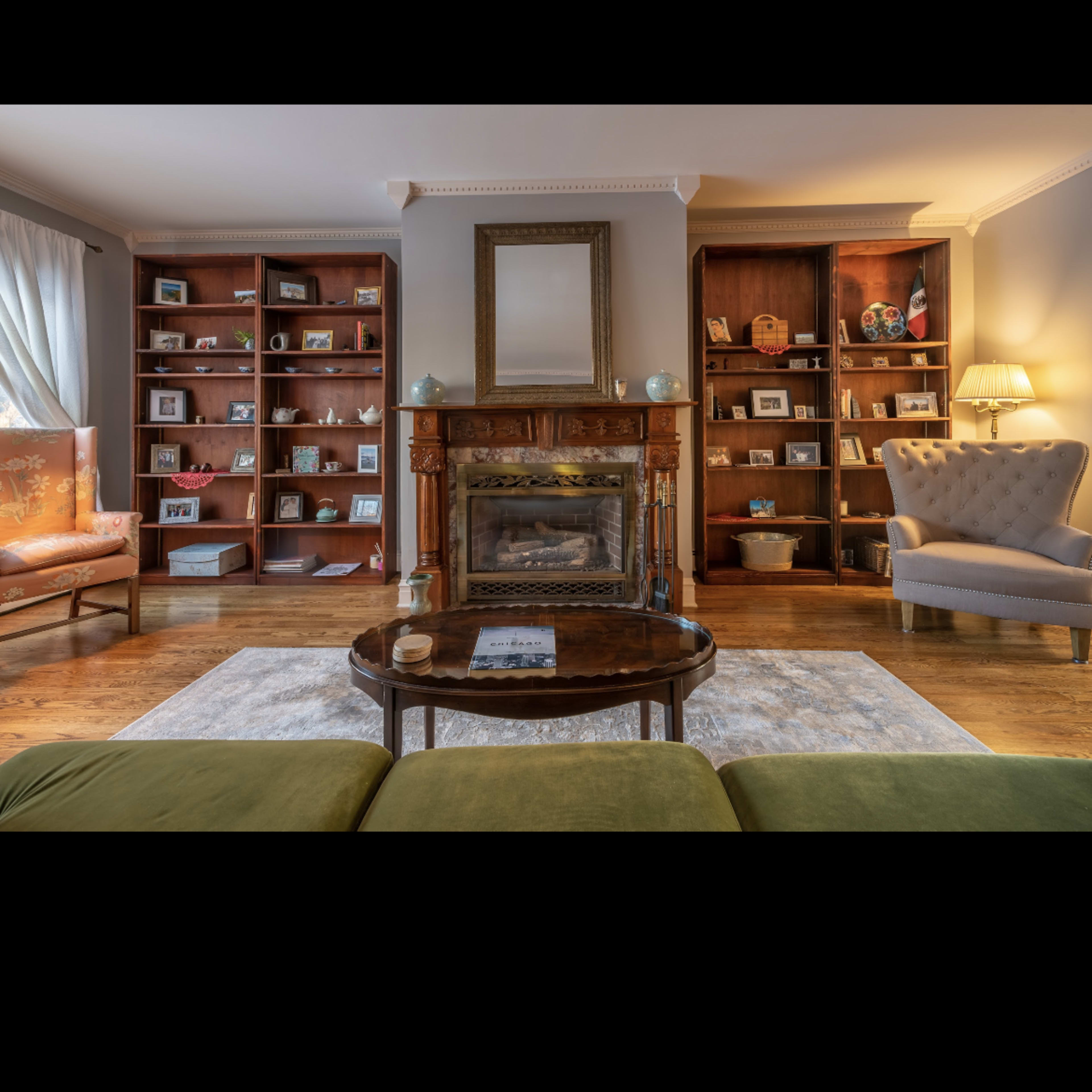 A living room with a central coffee table, a fireplace, and bookcases filled with framed photos and decorative items.