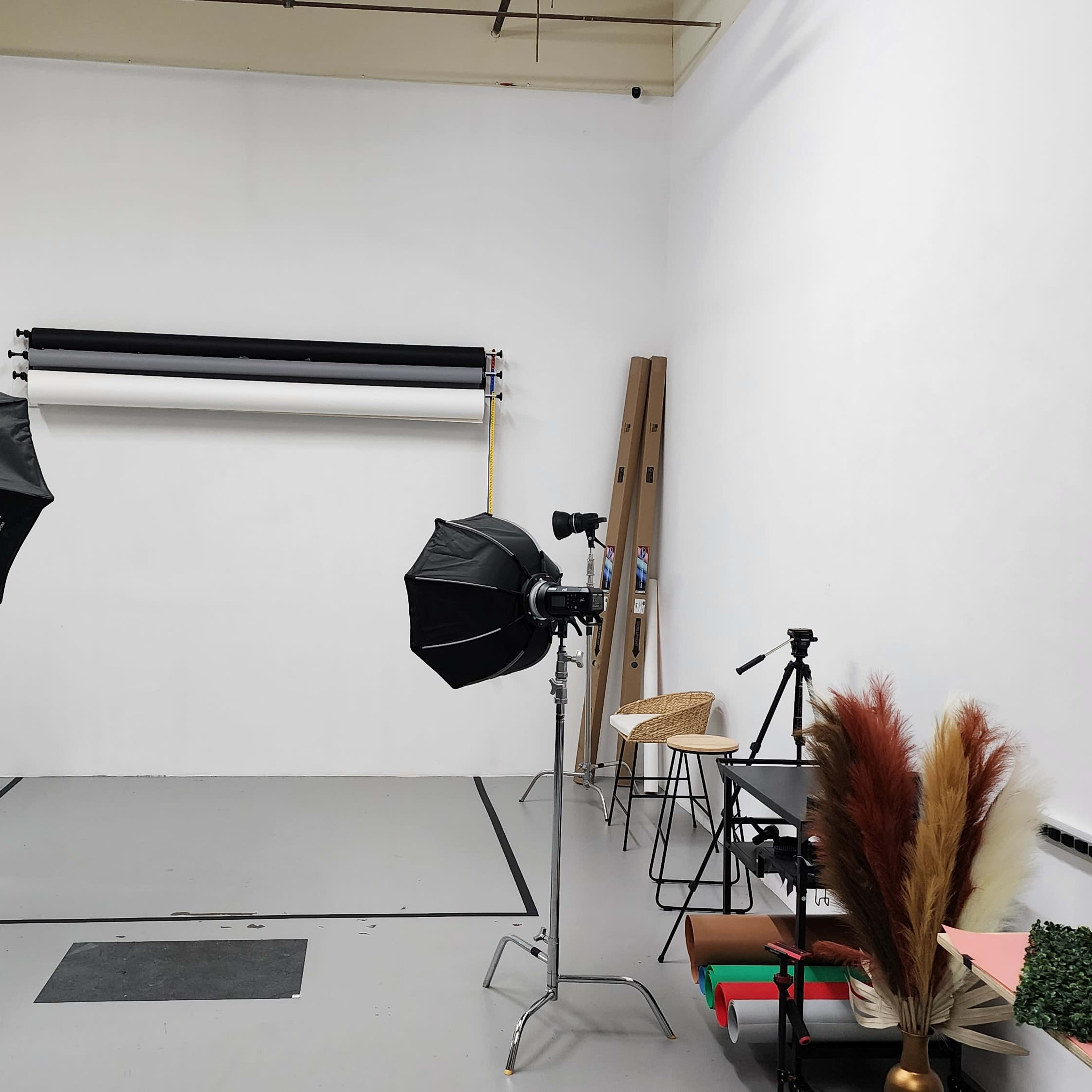 A photography studio equipped with light modifiers, backdrops, and a few props arranged on the floor.