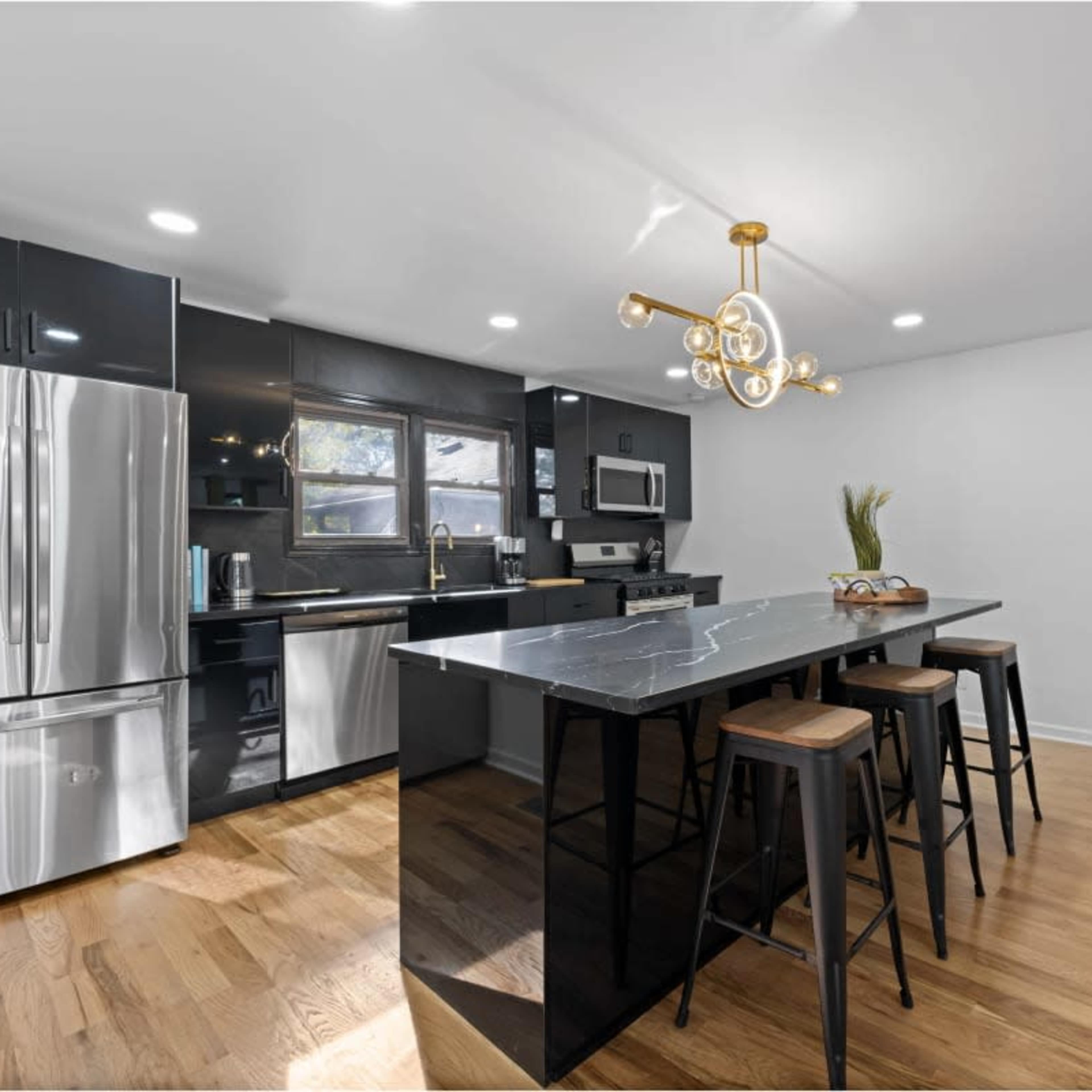 A modern kitchen features black cabinetry, stainless steel appliances, and a central island with seating.