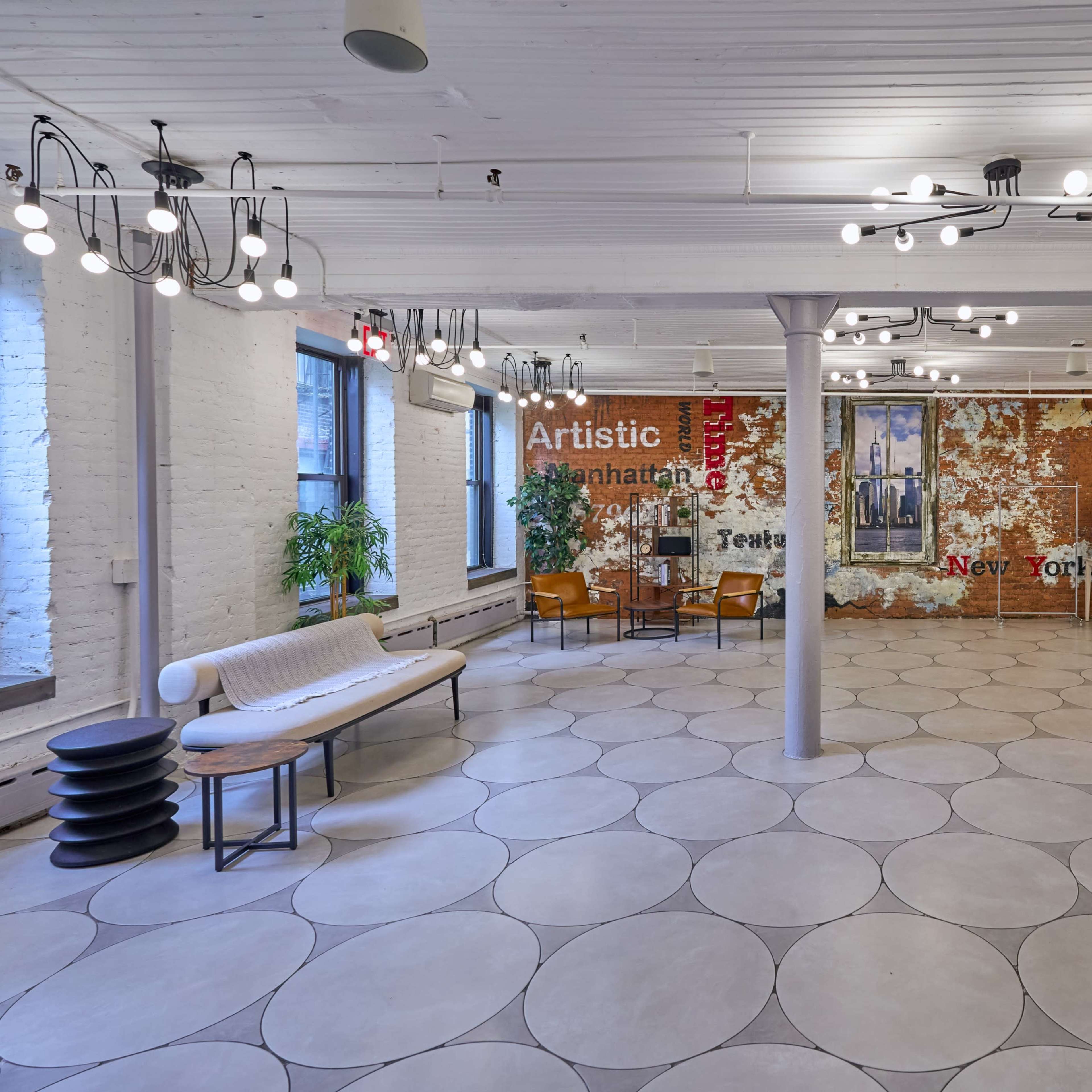 A spacious, modern indoor area featuring a light-colored tiled floor, brick accent wall with text, and various seating arrangements.